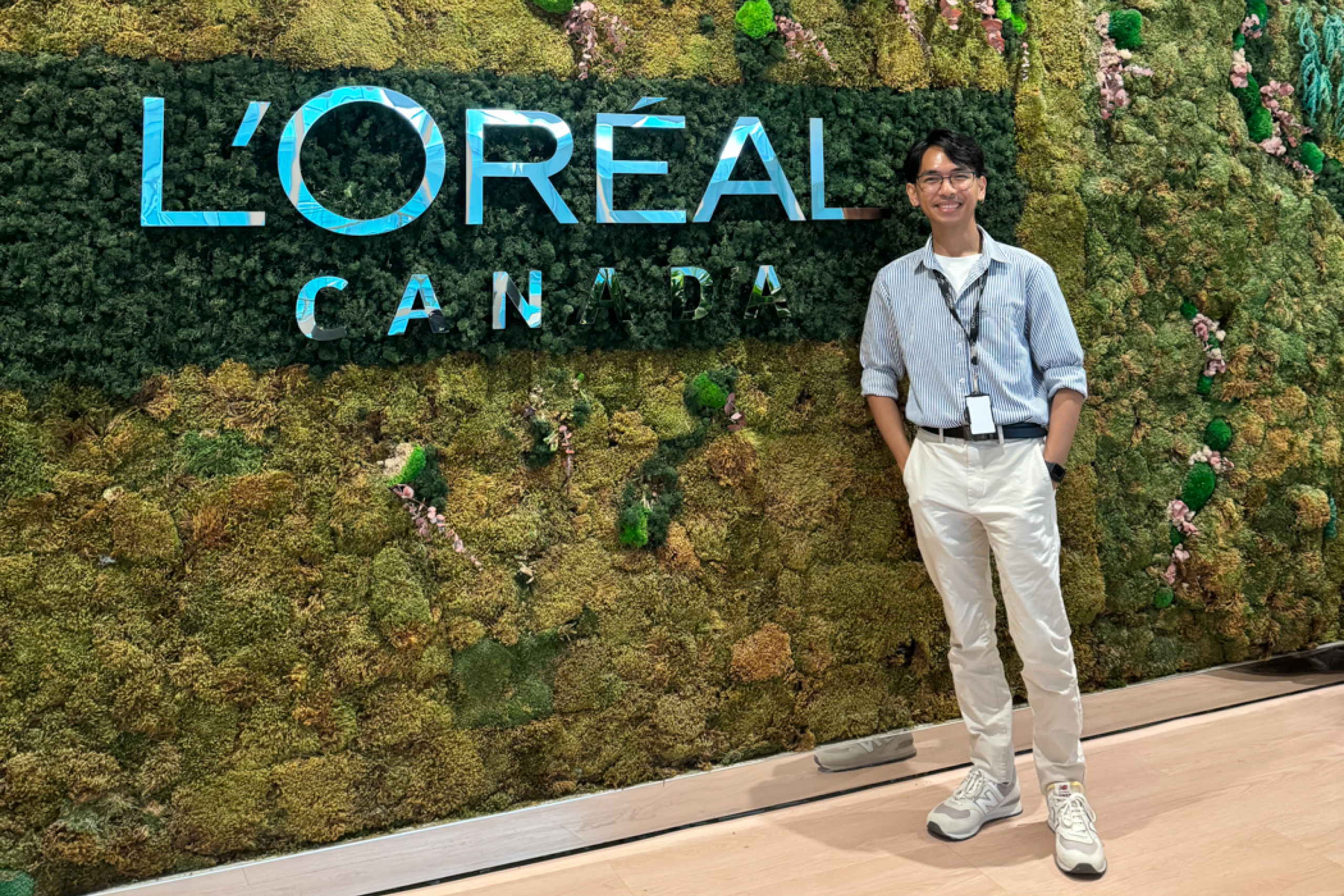 Jared Salvador smiling in front of a vertical garden wall featuring the L’Oréal Canada logo.
