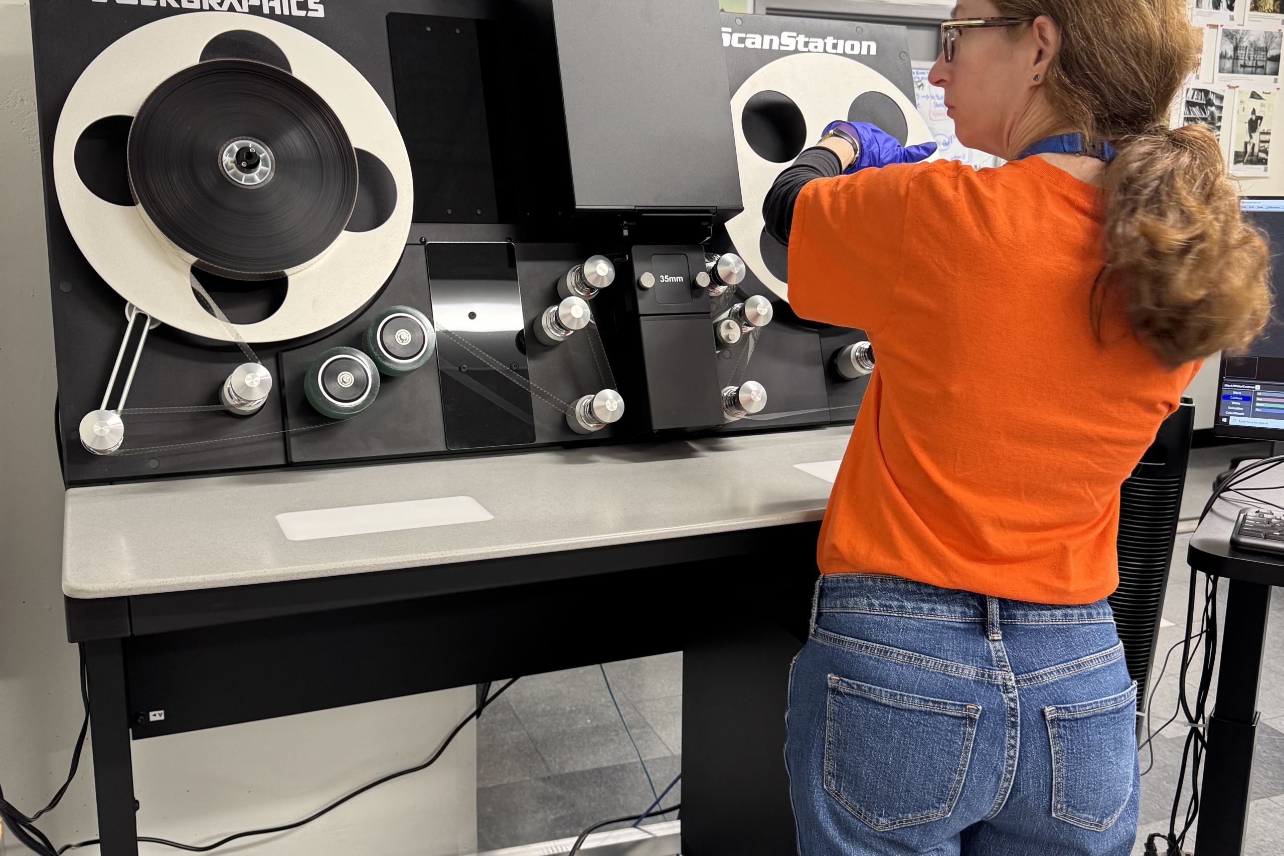 A woman threading film on a film scanner