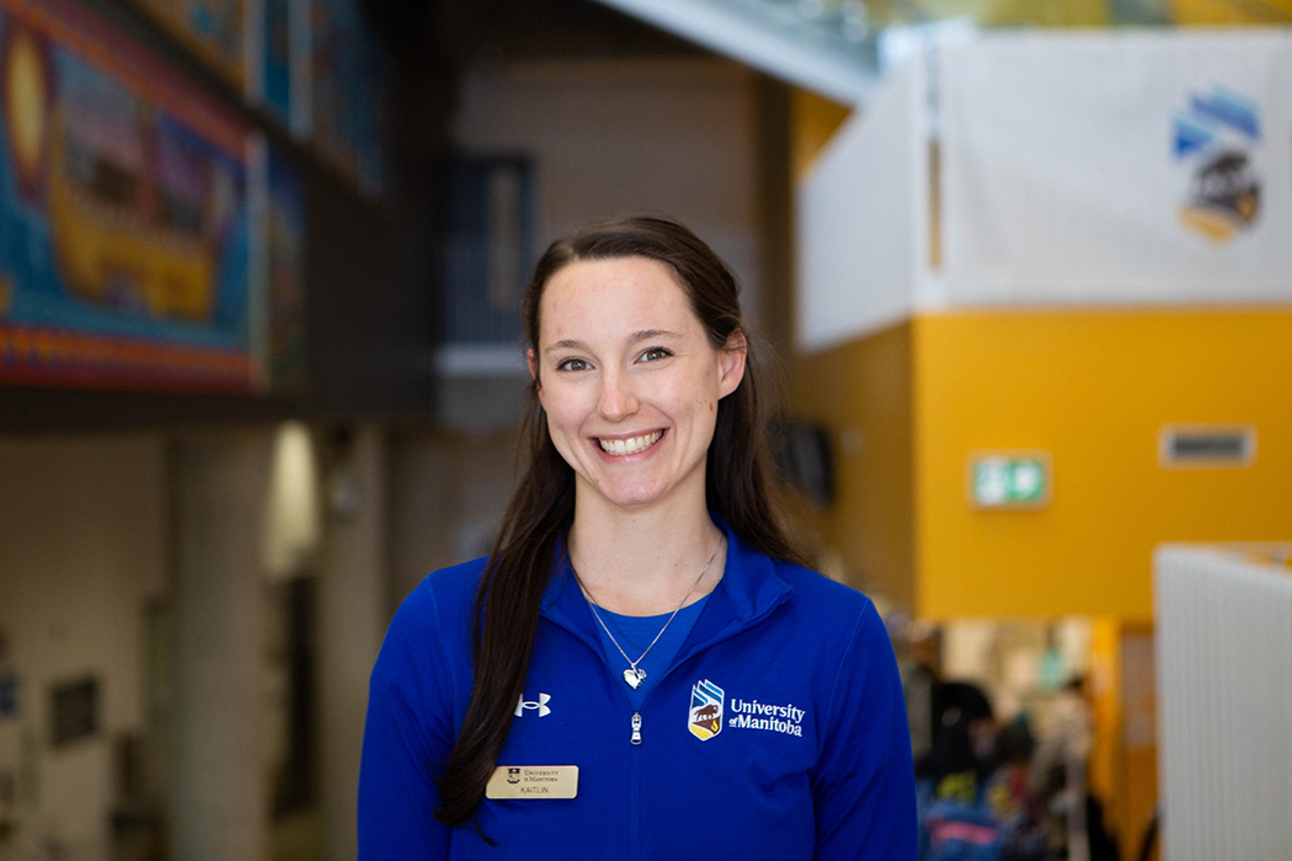 Kaitlin Reilly poses while wearing a University of Manitoba shirt and nametag.