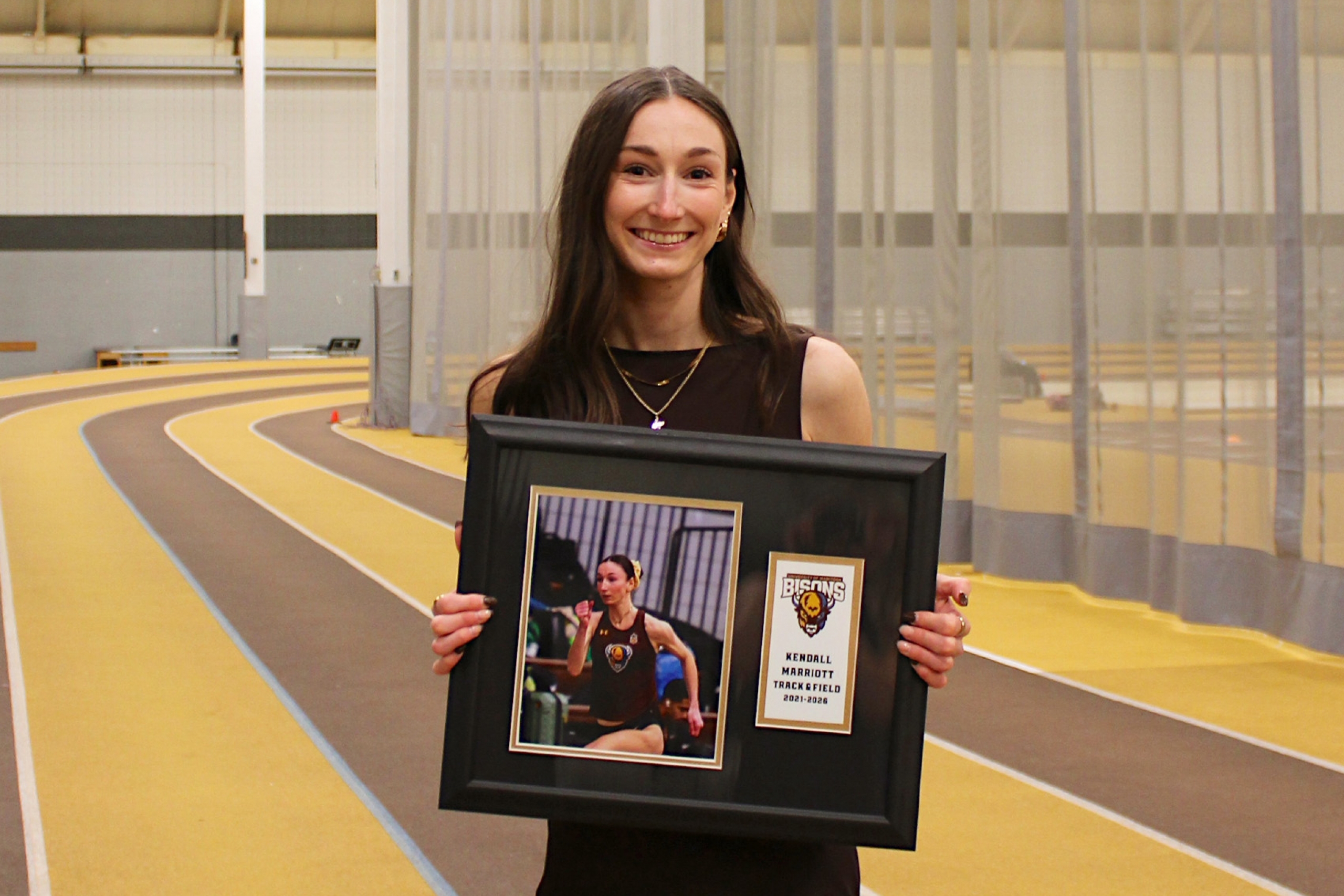 Kendall Mariott holding her fifth year photo on the track