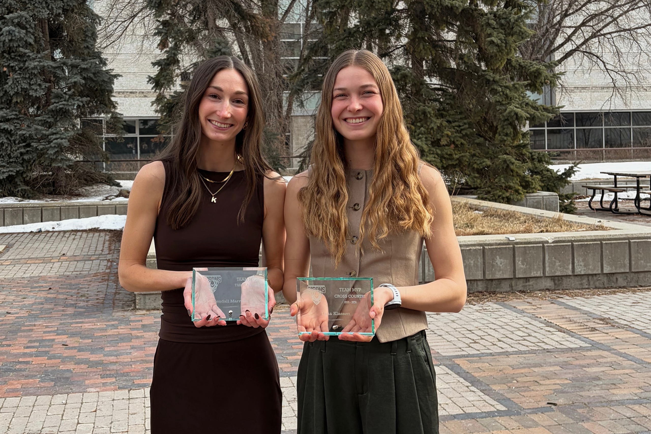 Kendall Mariott and Lena Klassen posing outside with their team MVP trophys