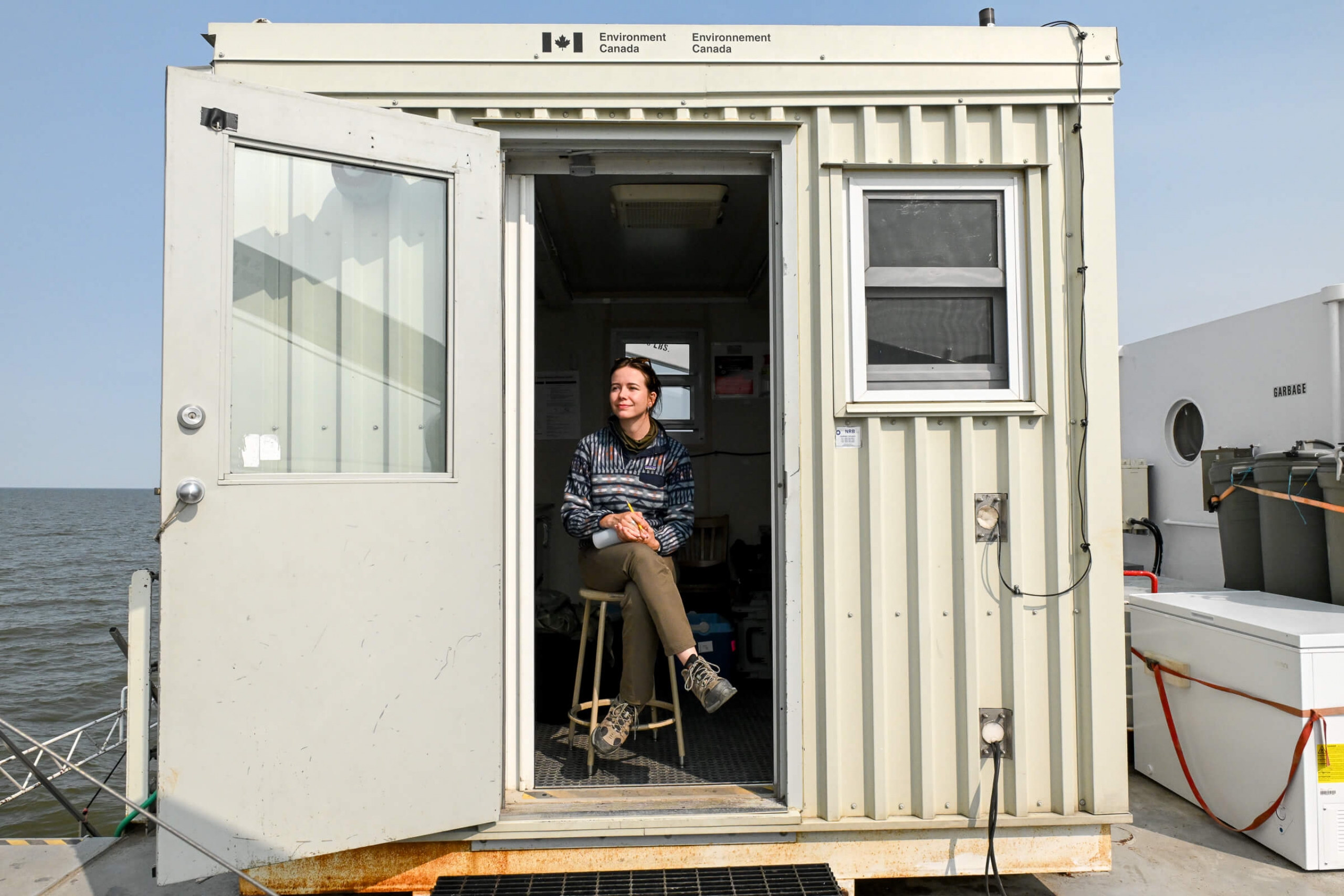 A woman sits in a doorway on a boat facing the outside