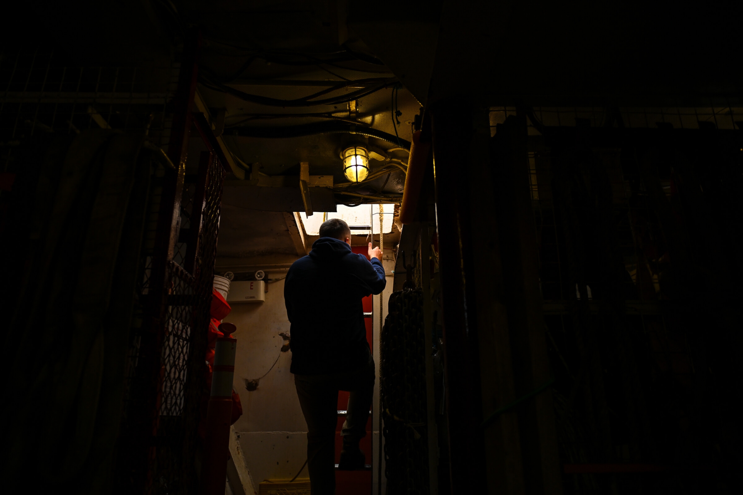 A man climbs up a ladder inside the boat towards the outside