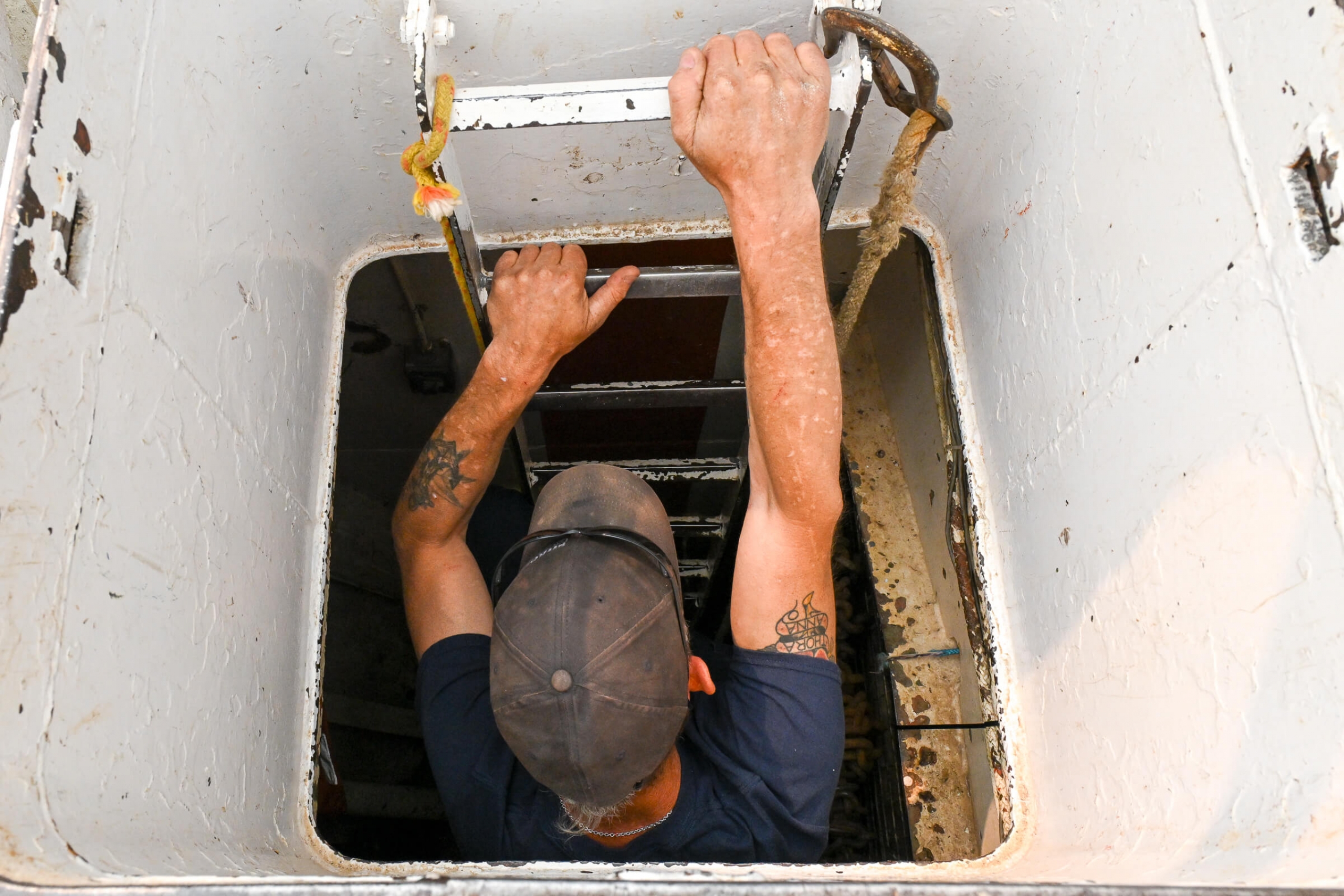A man lowering himself on a ladder into a boat