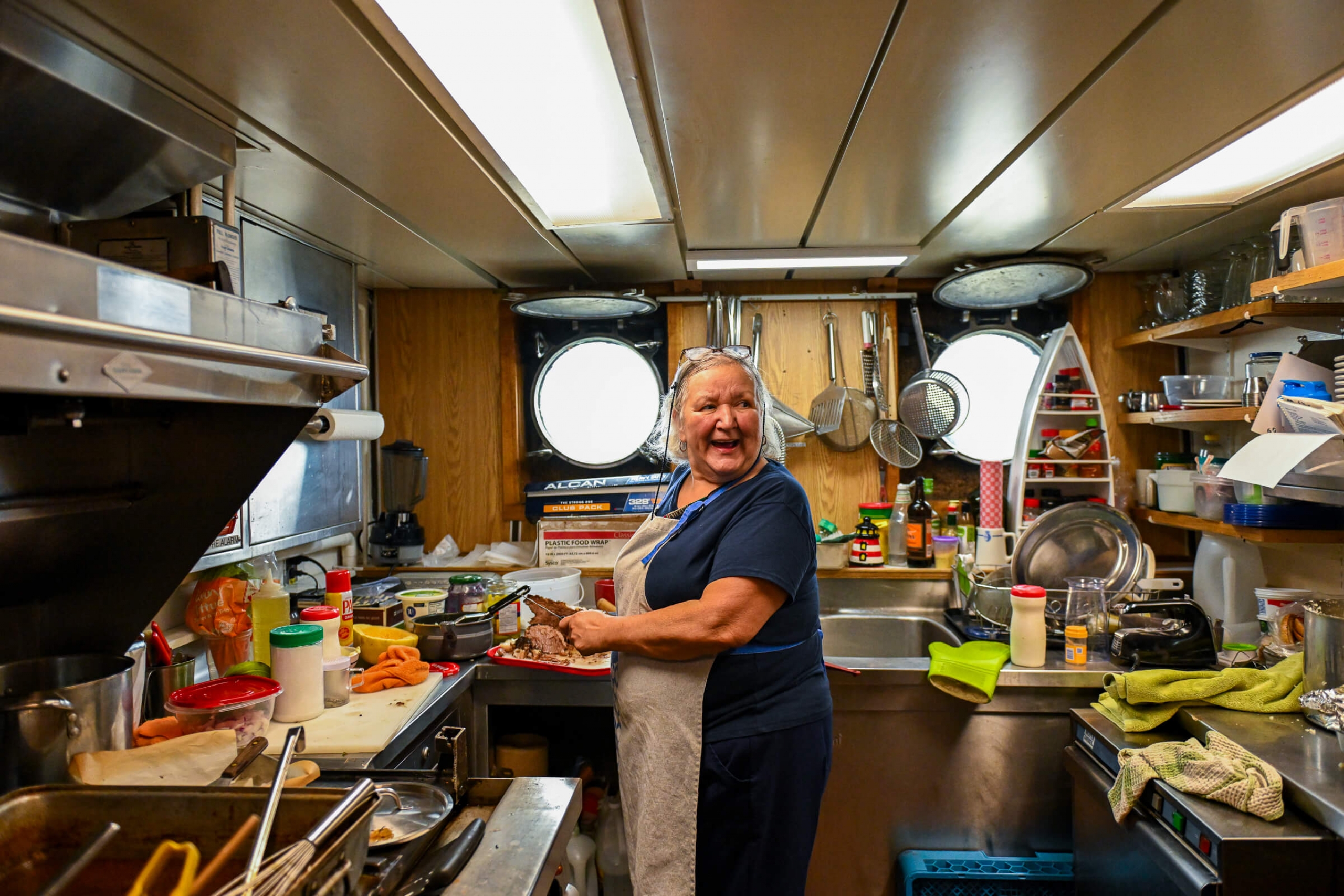 A smiling older woman in the kitchen of the boat