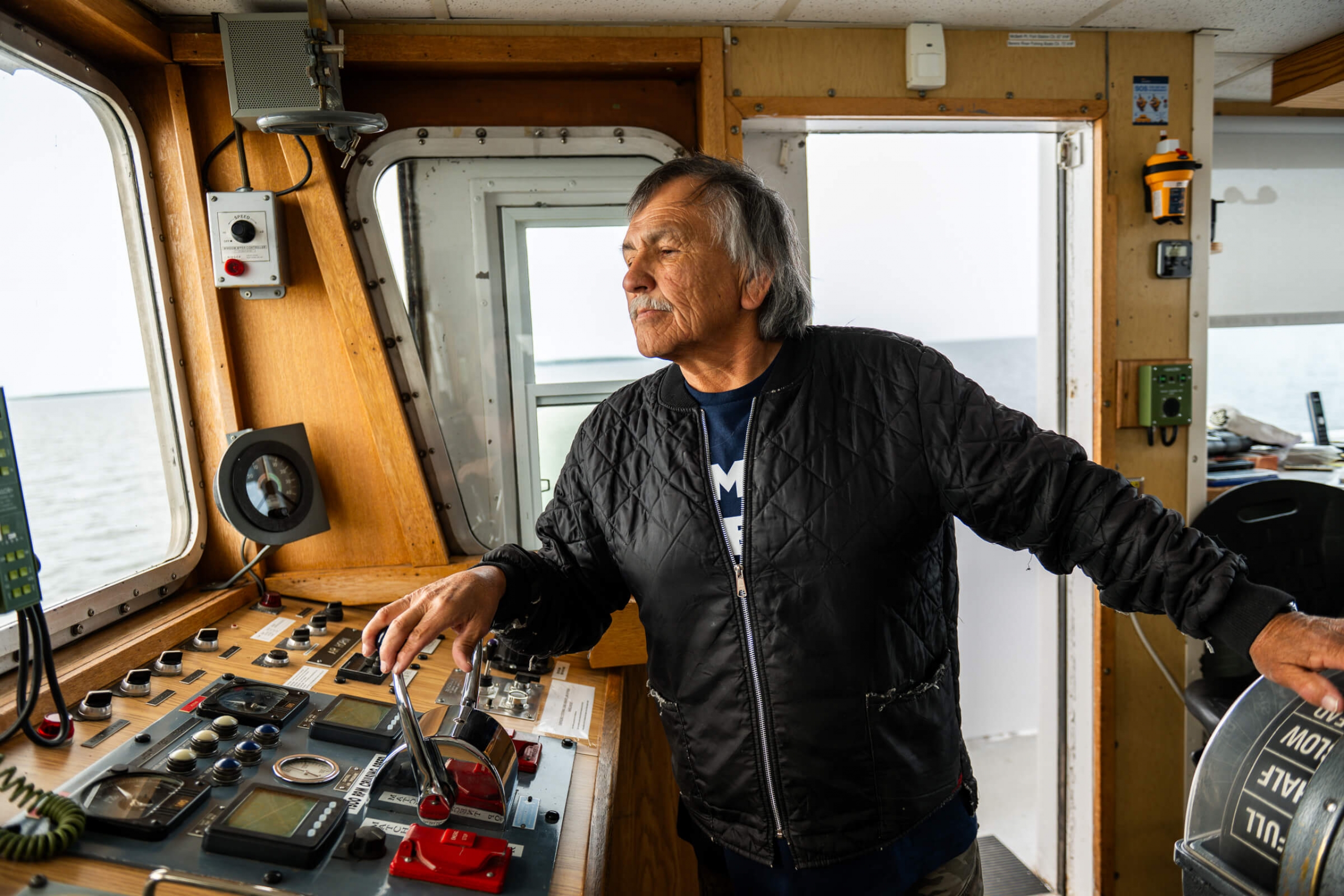 A man (Captain Lee) adjusts the boat's thruster in the cockpit