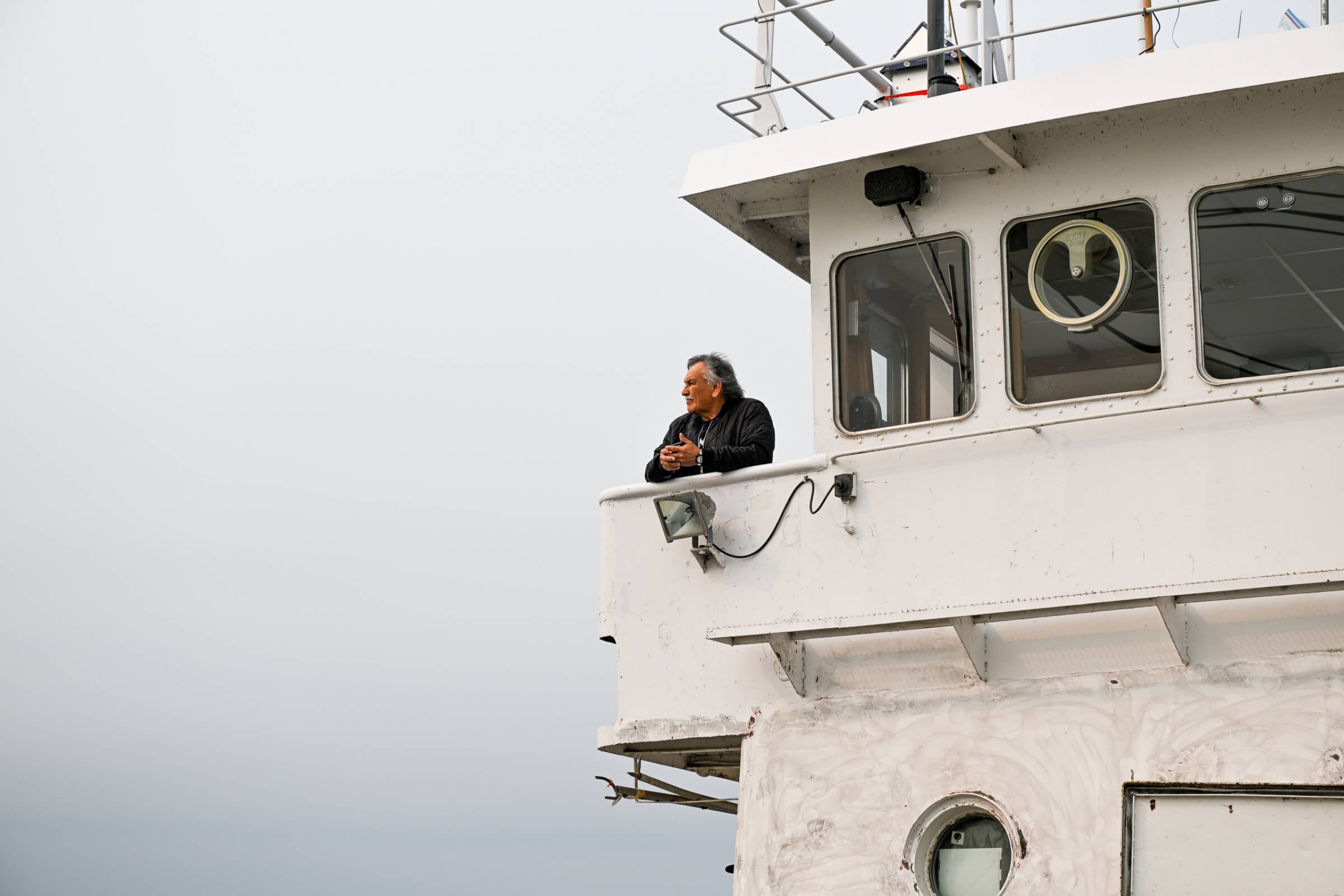 A man (Captain Lee) observes the boat and the lake from the upper deck