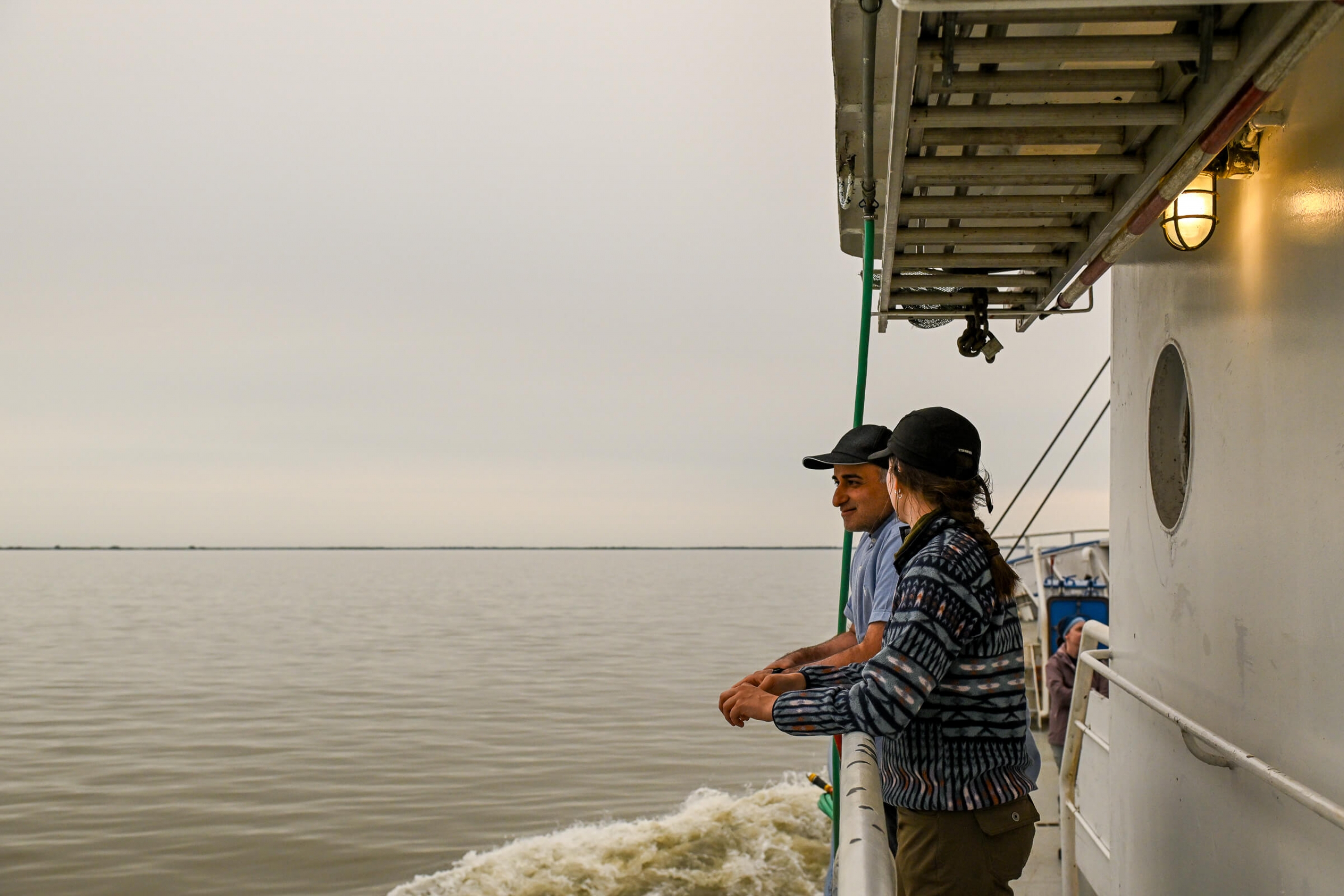 A man and a woman in coversation leaning over the rails on a the boat deck
