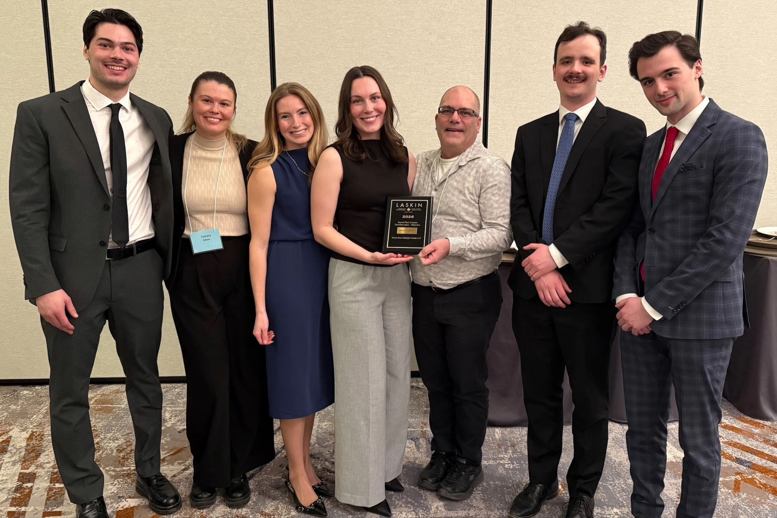 seven people stand around a plaque that they have won as a team for the Laskin moot second place factum