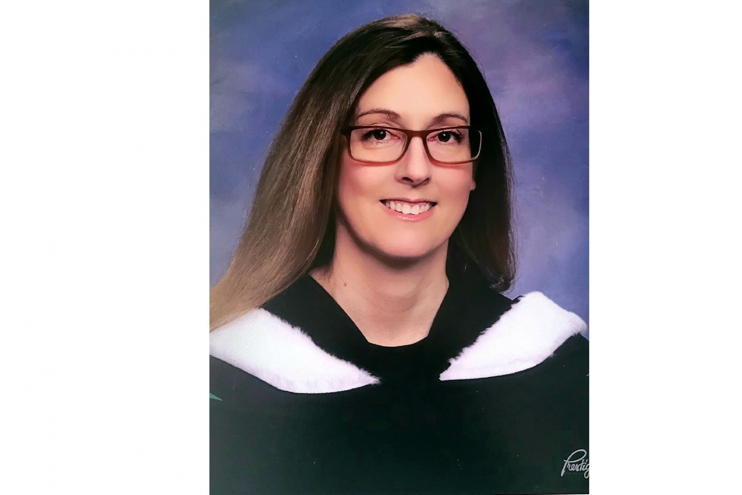 Laura Taylor in a graduation headshot wearing a gown.