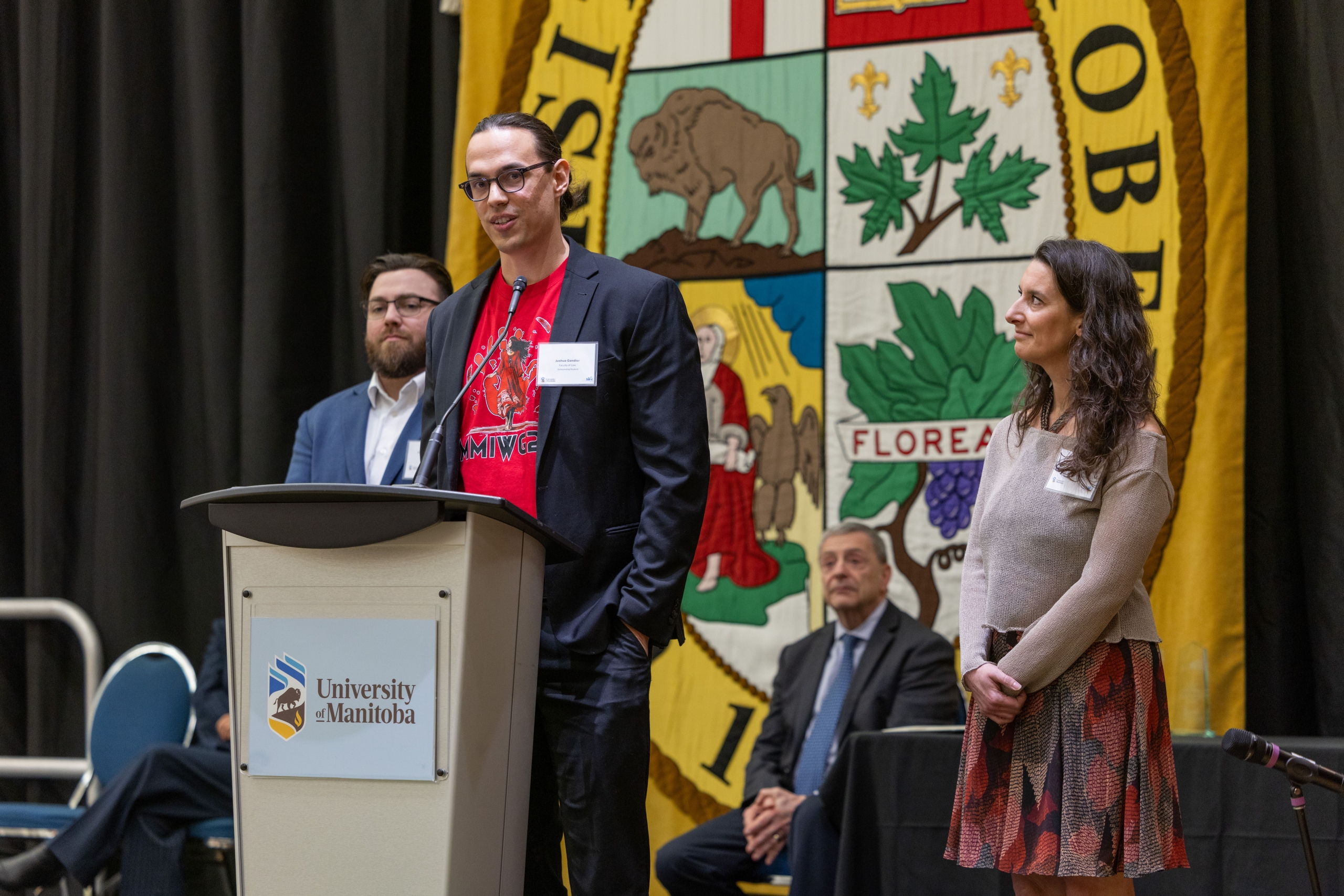 Joshua Gandier gives his speech on stage next to his former educators.