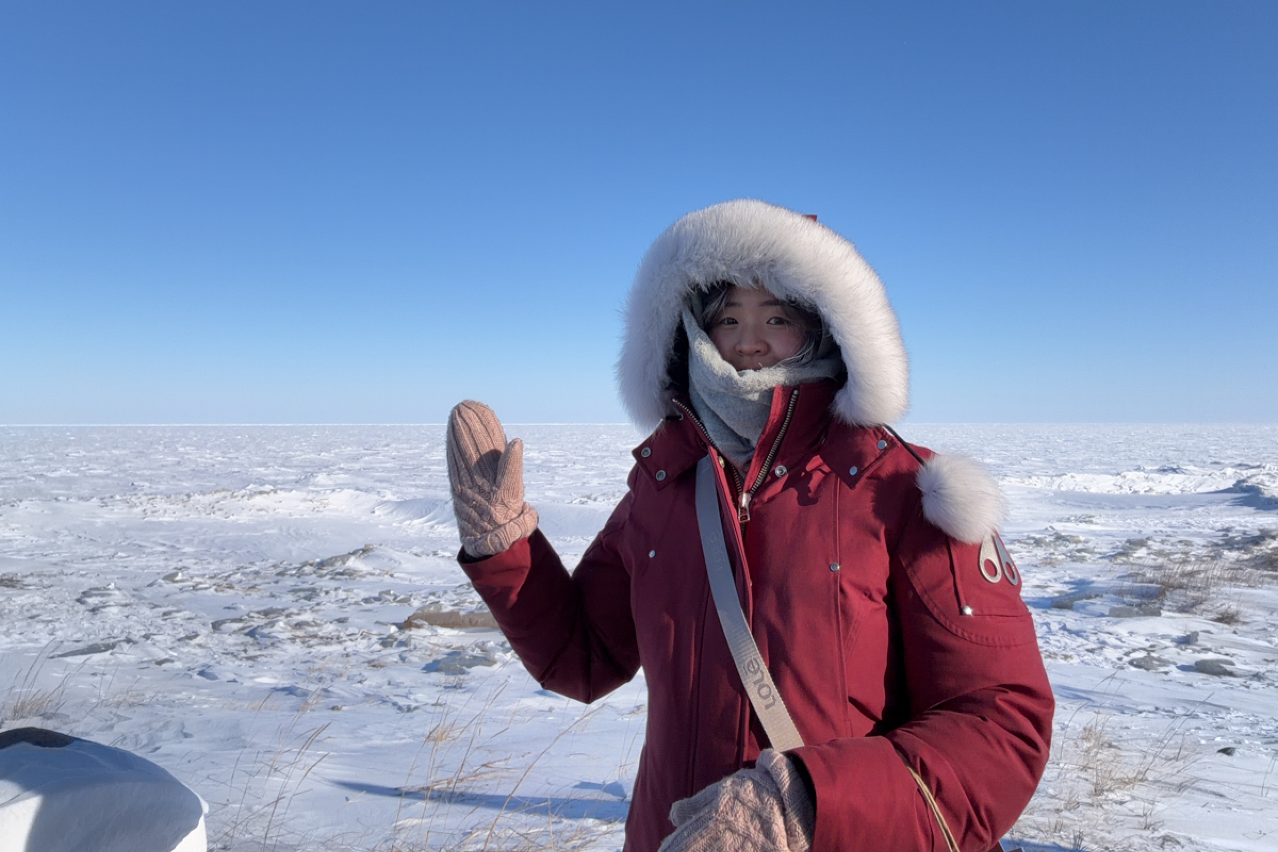 A person poses for the camera in front of a frozen Hudson Bay.