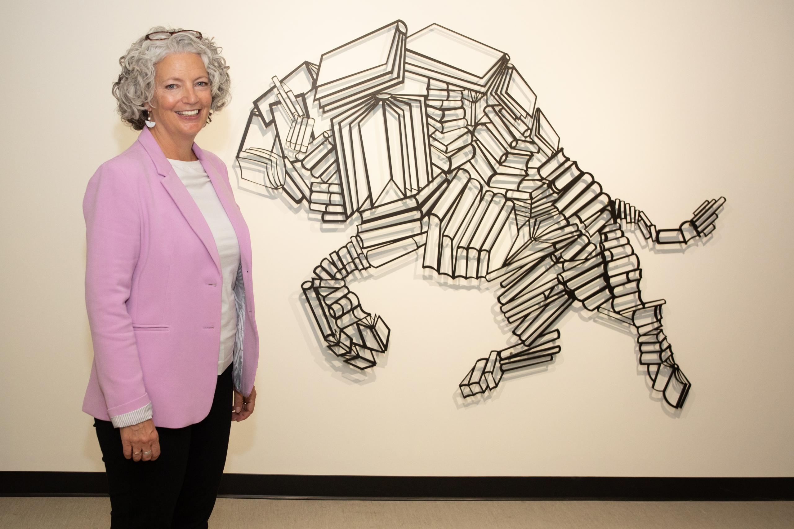 Lisa O'Hara standing by the steel bison-and-books art installation