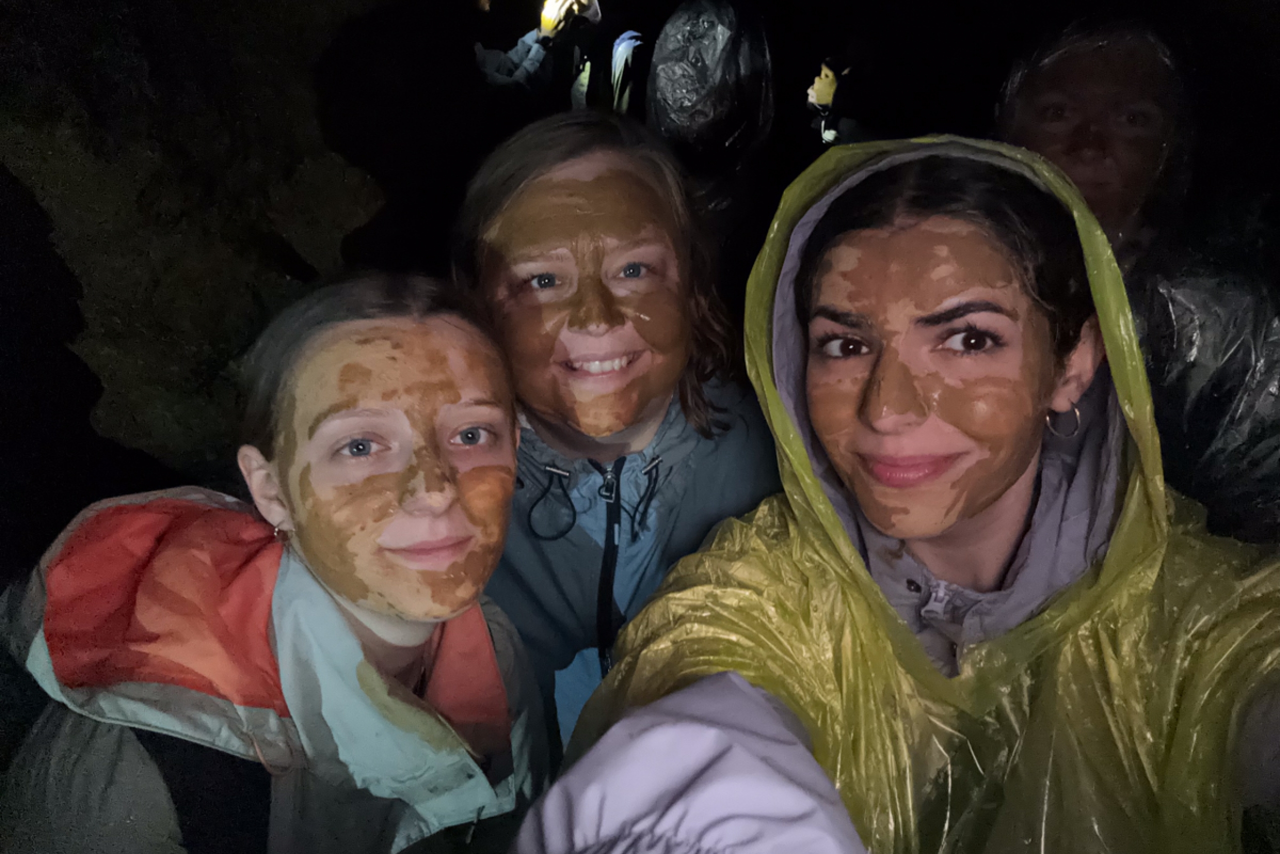 Four people in a cave with mud on their faces.