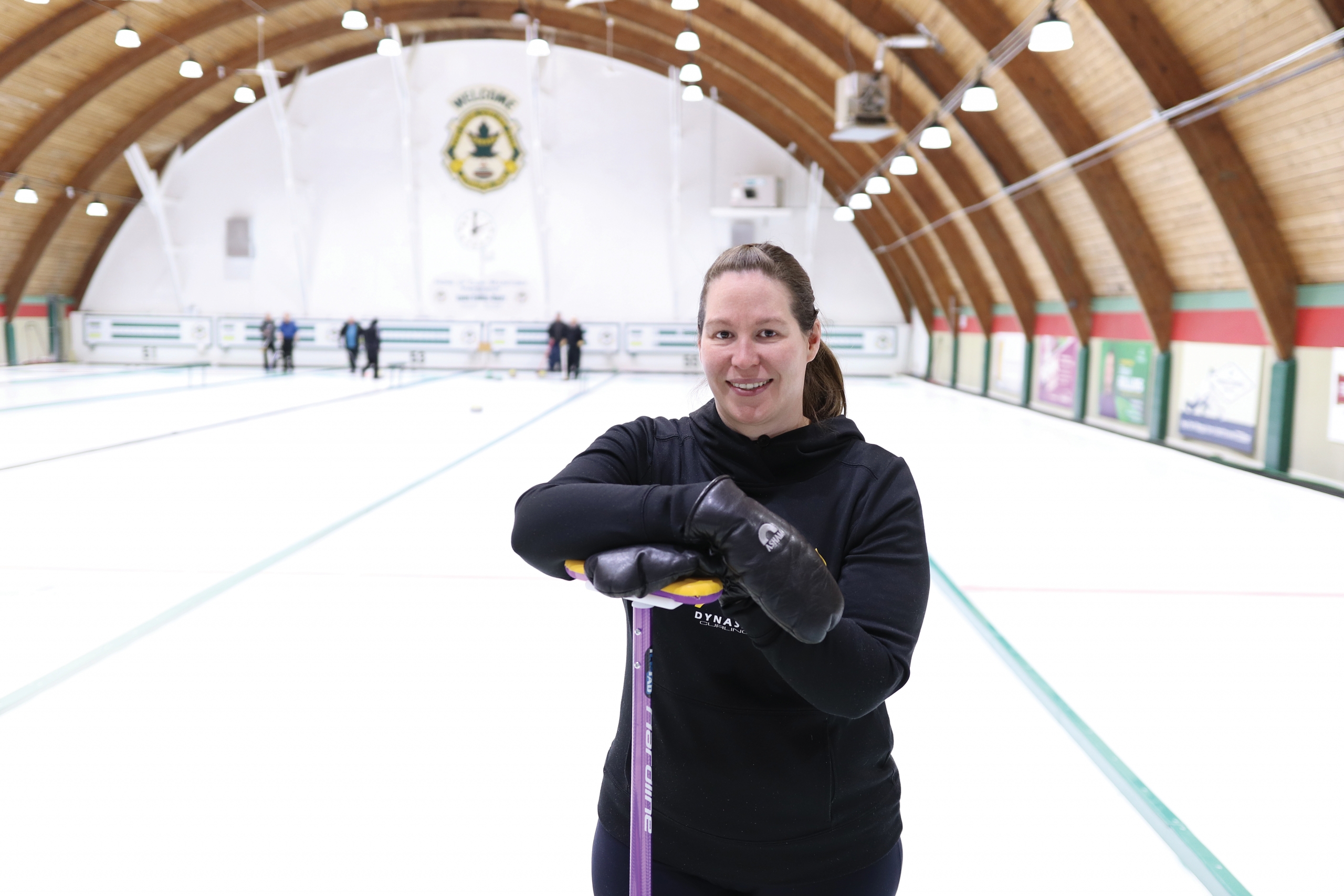 Lisa Bartley stands inside a curling club.