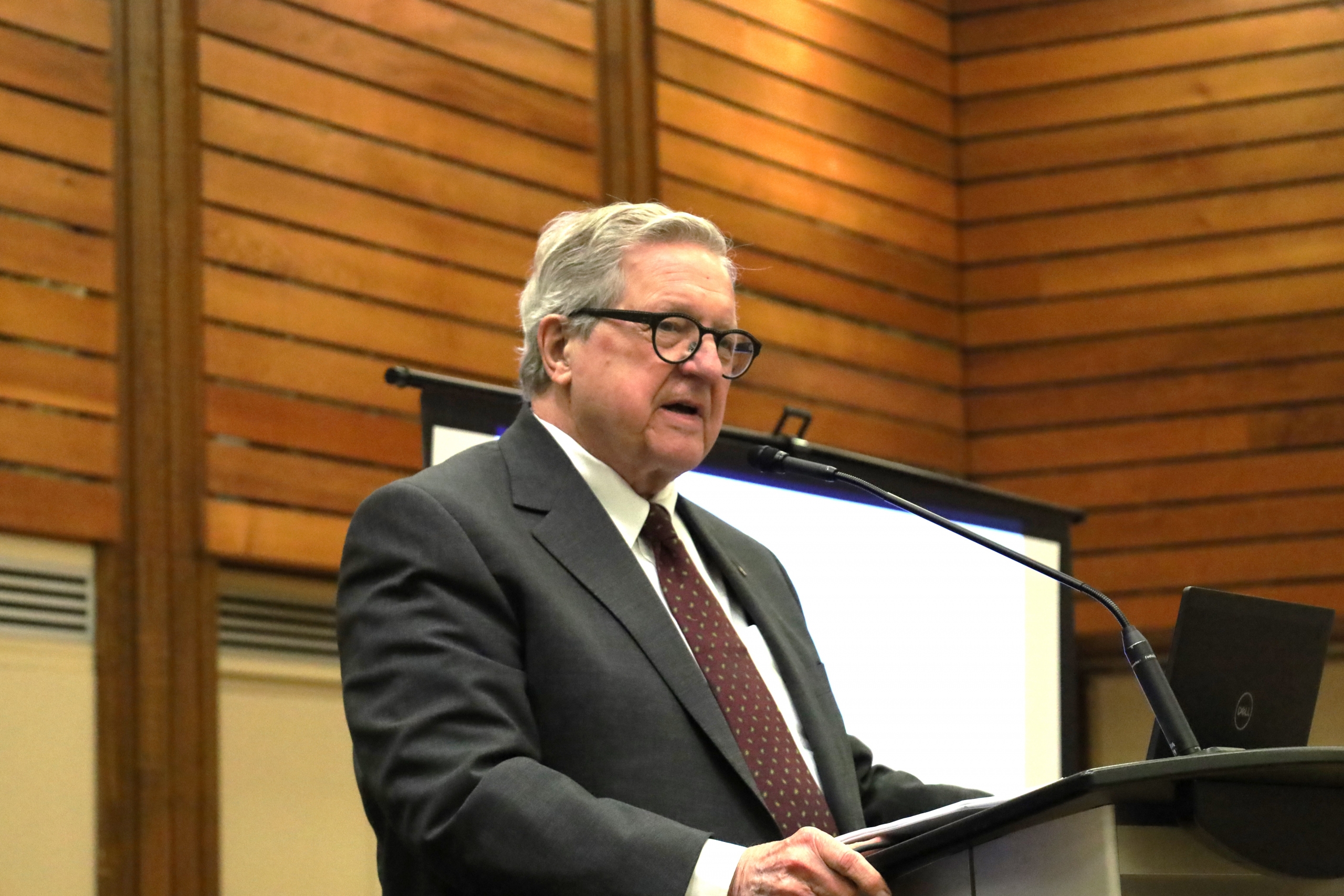 Lloyd Axworthy speaking into a podium microphone.