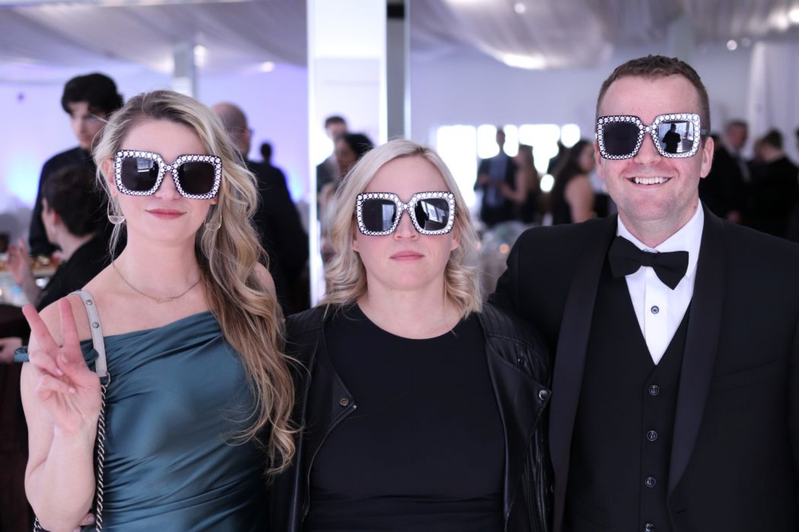 Three people pose for a photo wearing sunglasses. 