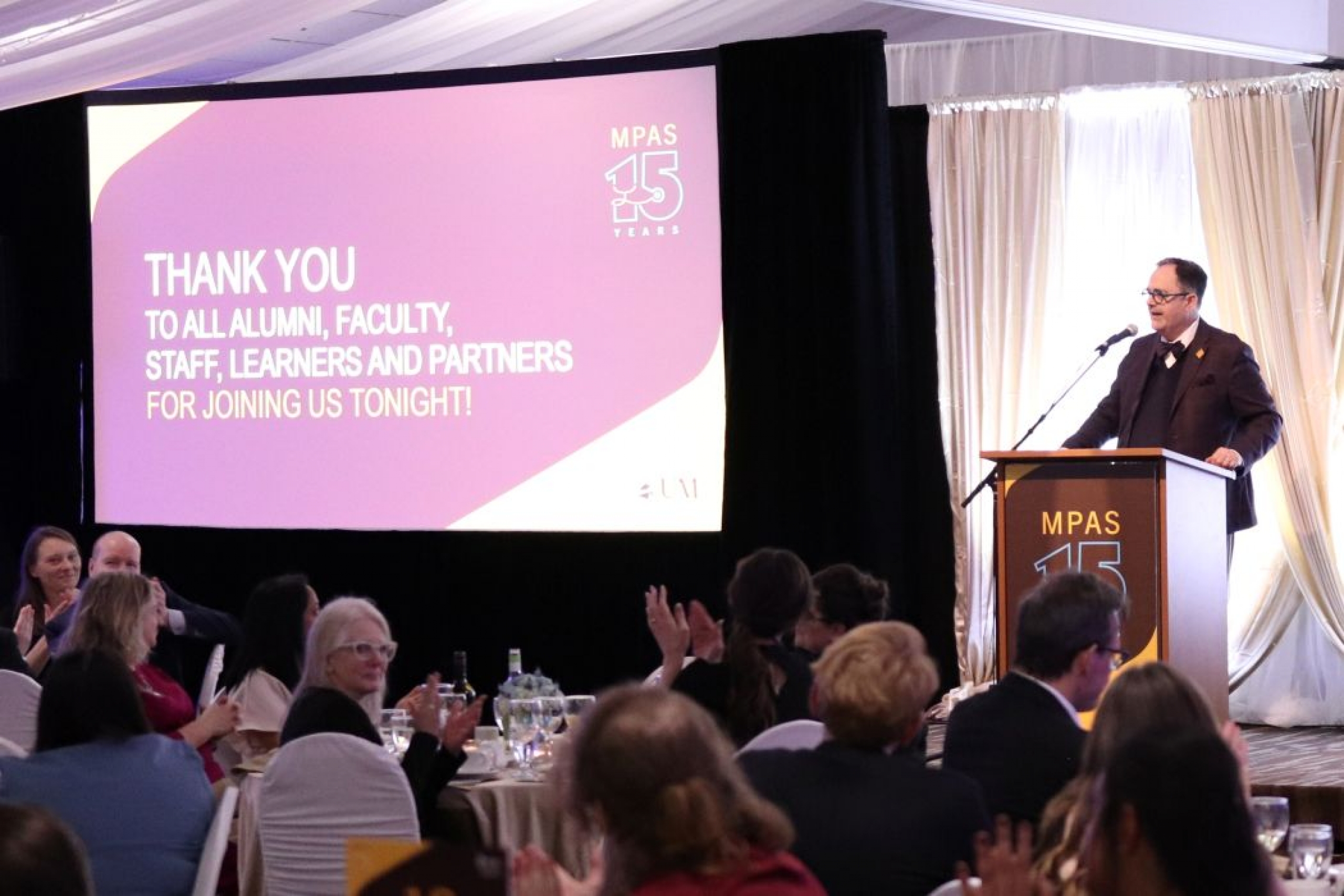 Dr. Peter Nickerson speaks at a lectern in front of an audience. 