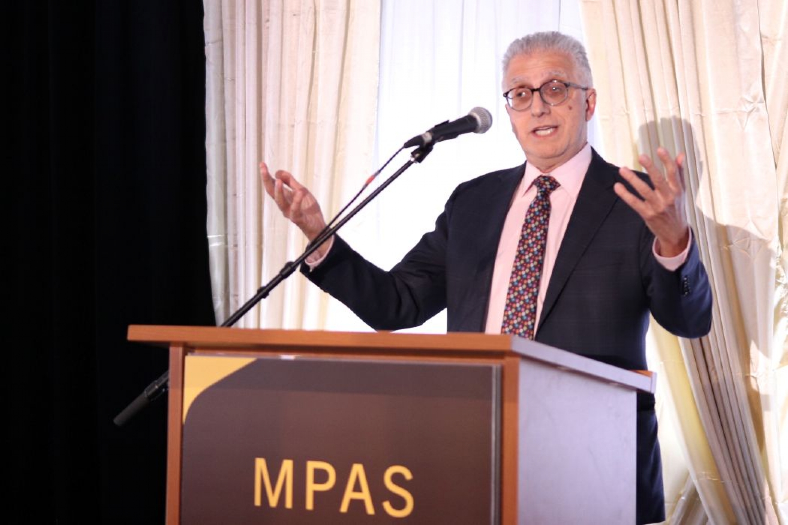 Dr. Michael Benarroch speaks at a lectern. 