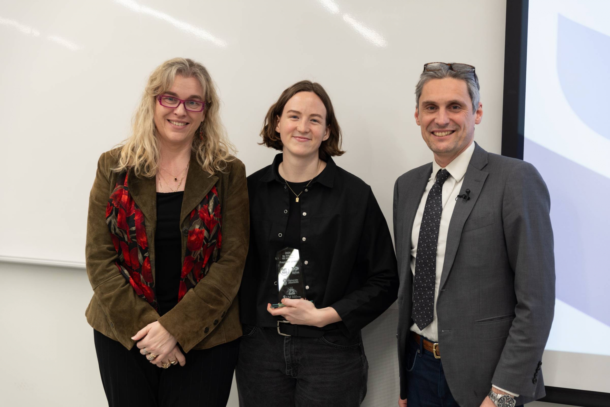 A man and a woman presenting an award to a student