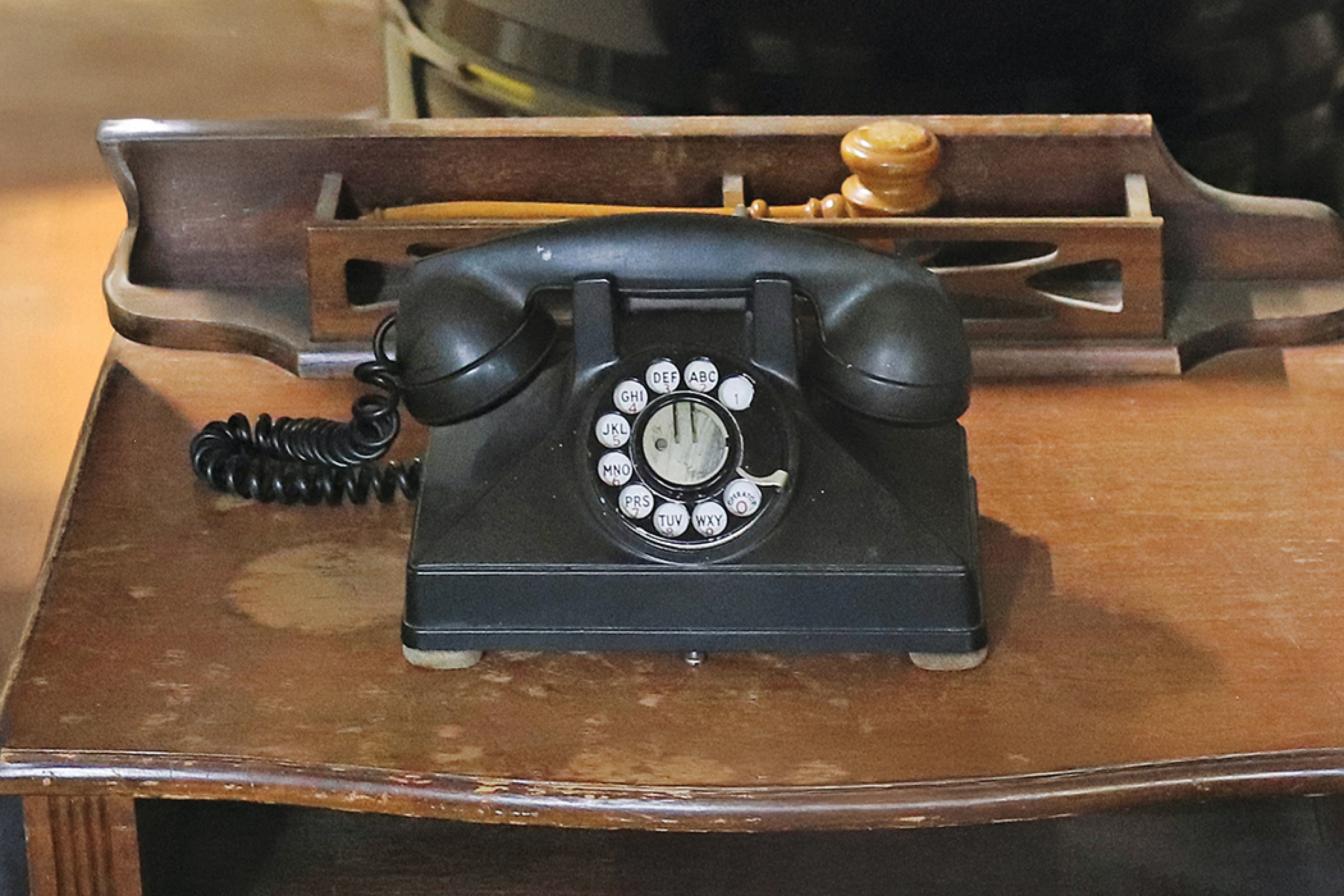 An old black rotary phone on a wooden desk.
