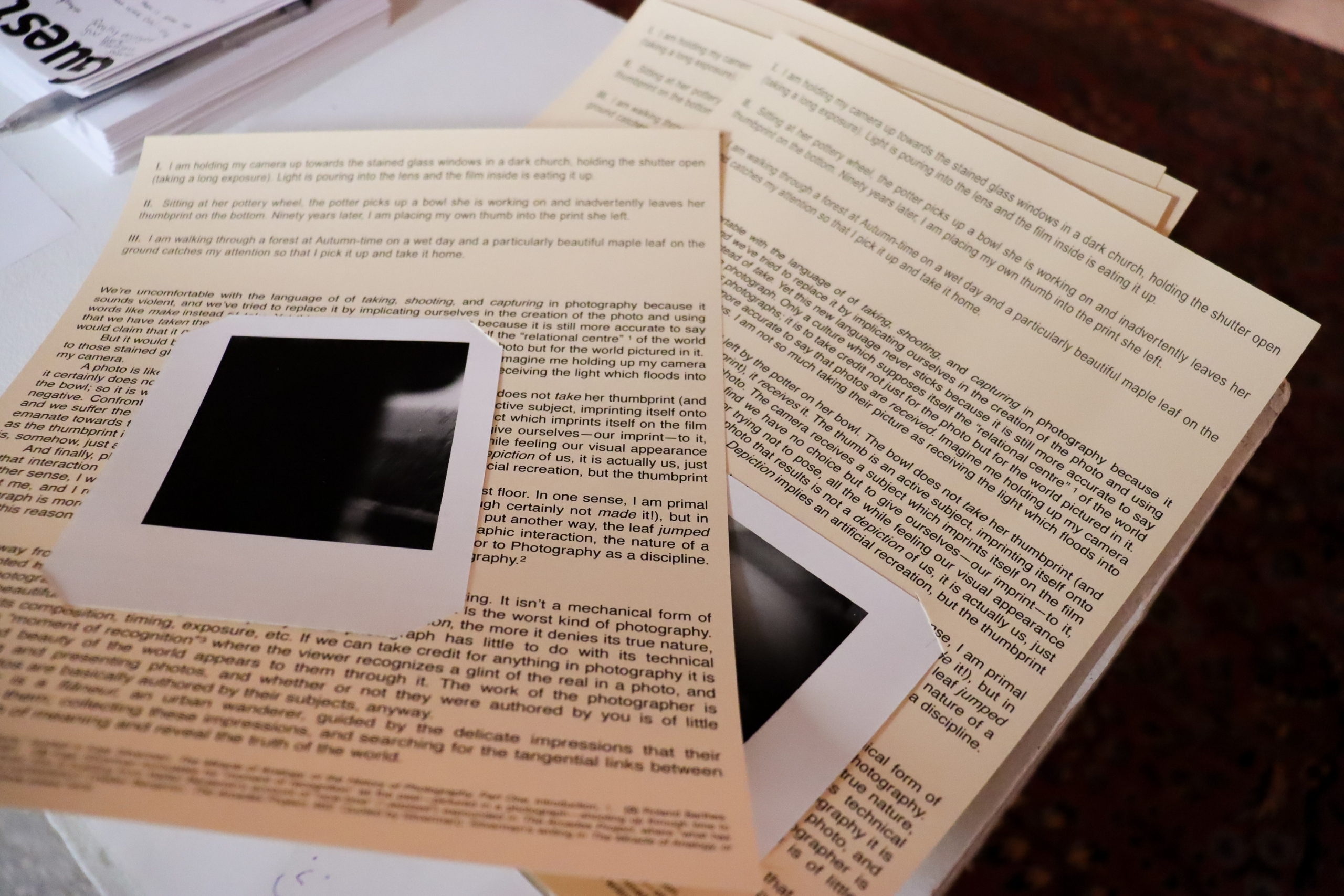 Printed artist statements and small photographs laid out on a table.