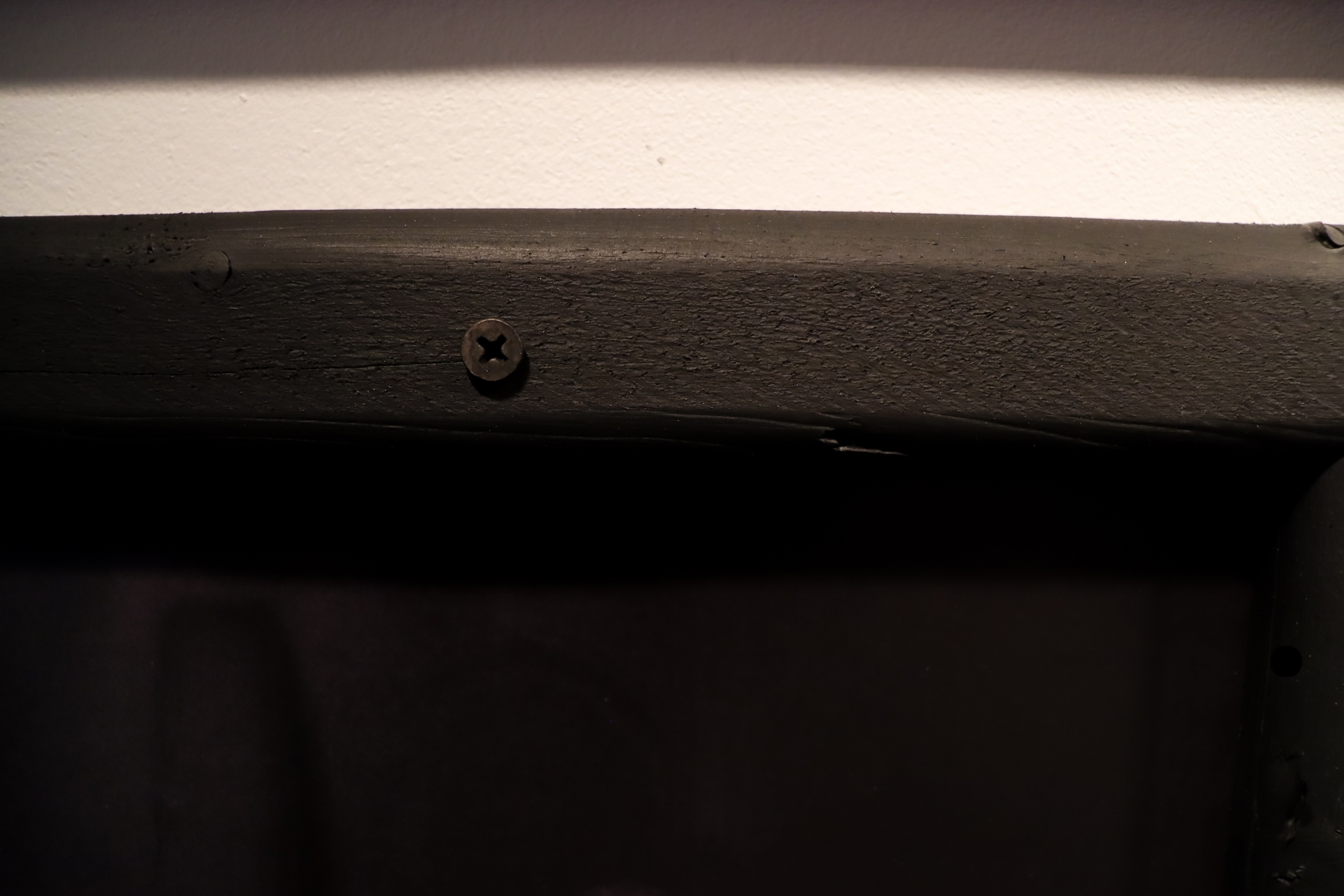 Close-up of a black wooden frame with a visible screw.