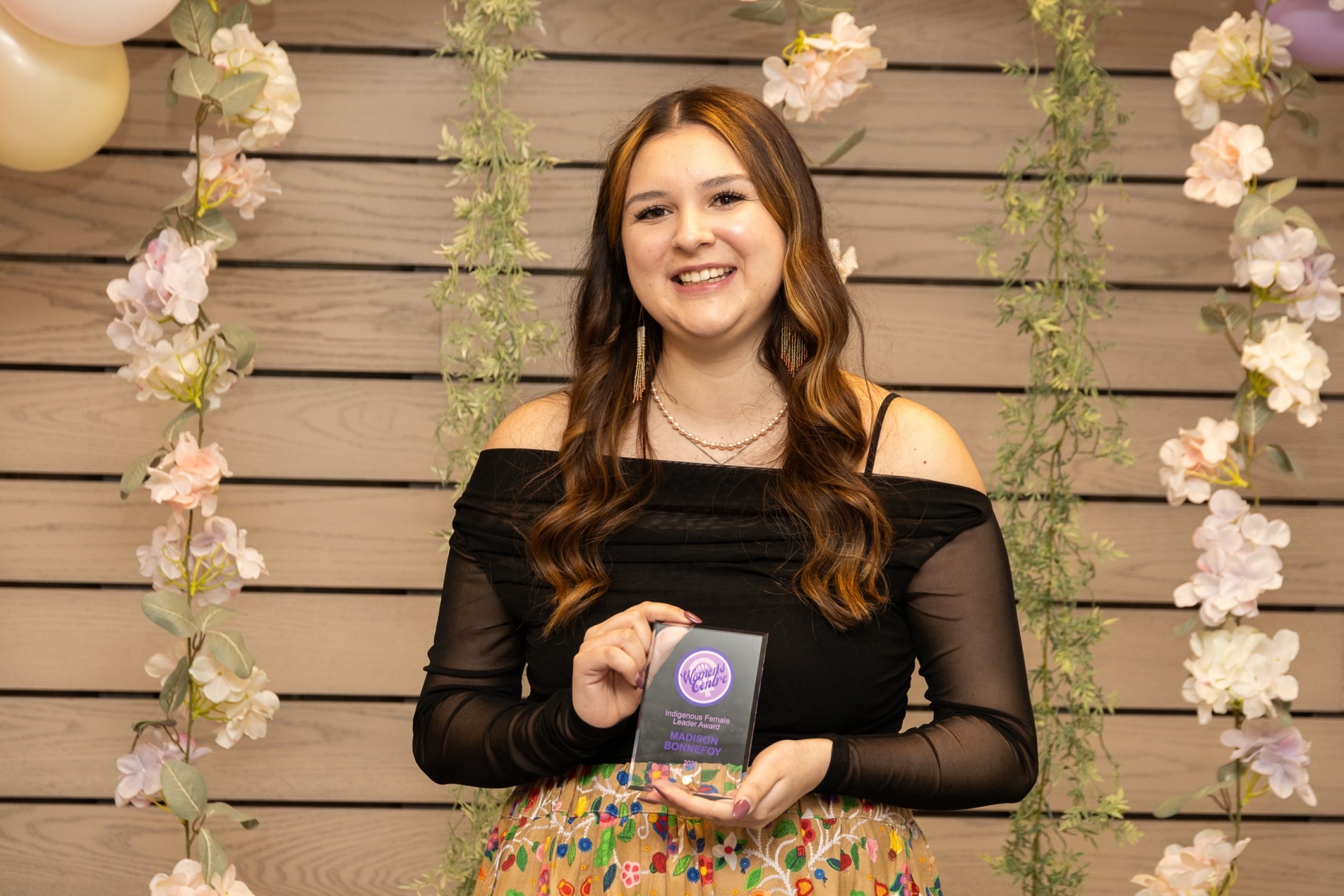 Madison holding an award, wearing a ribbon skirt and black blouse.