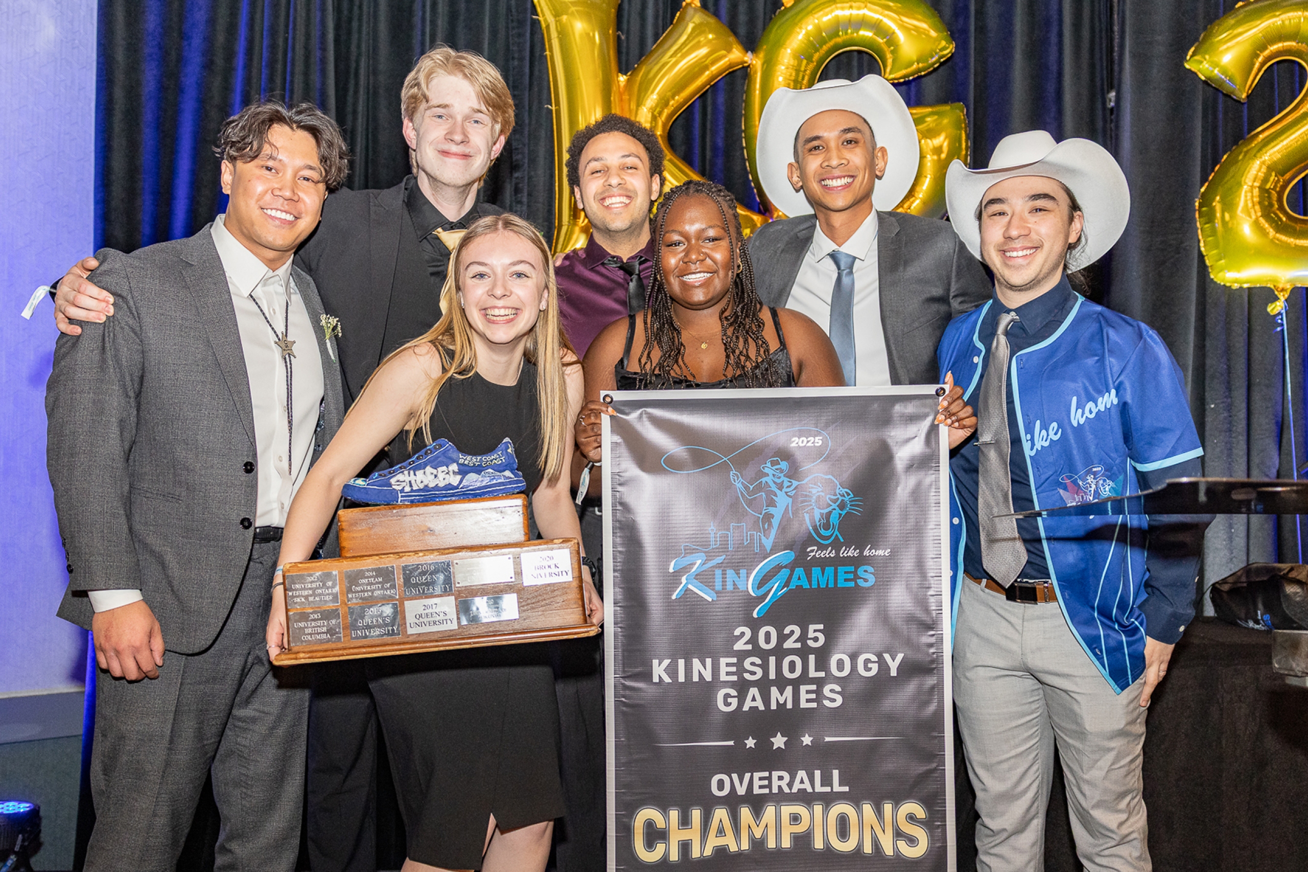 Seven students pose with the 2025 championship banner and tropy
