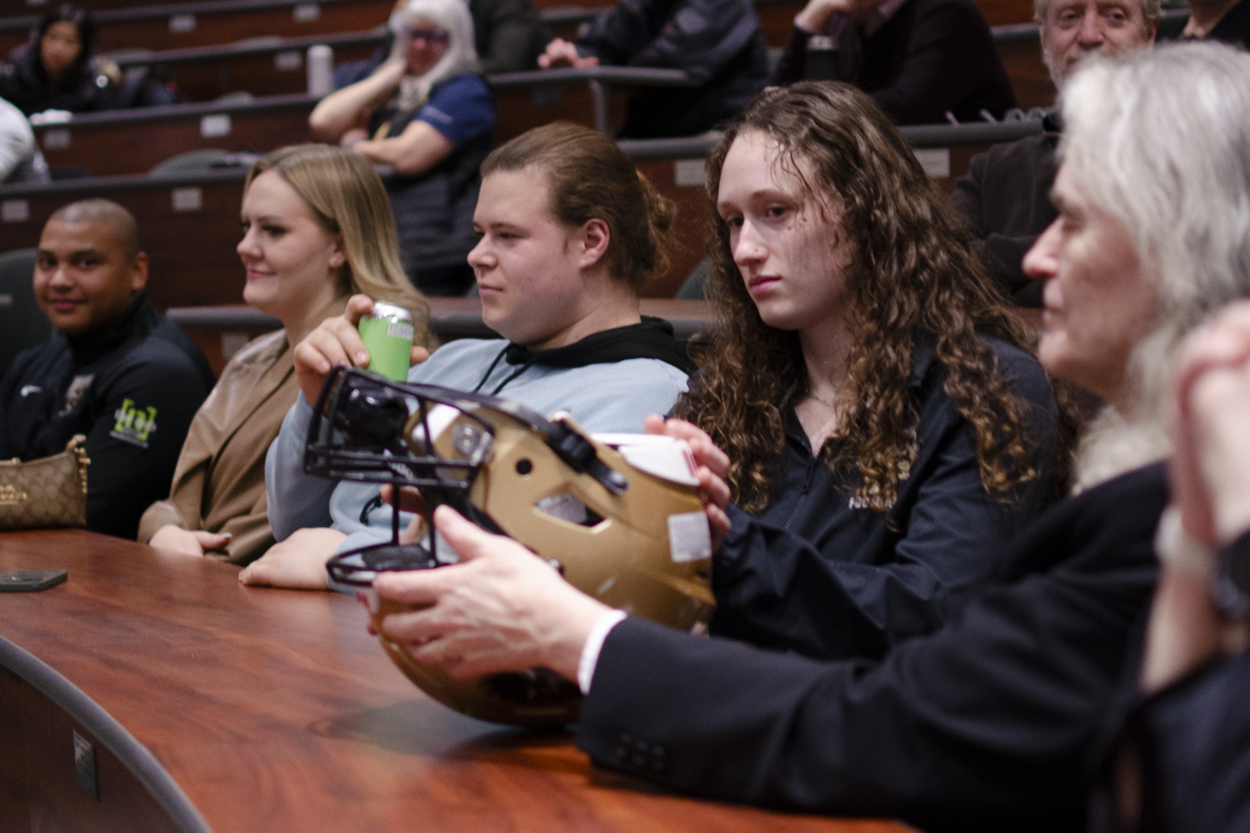 Maya Turner holding a football helmet at the lecture