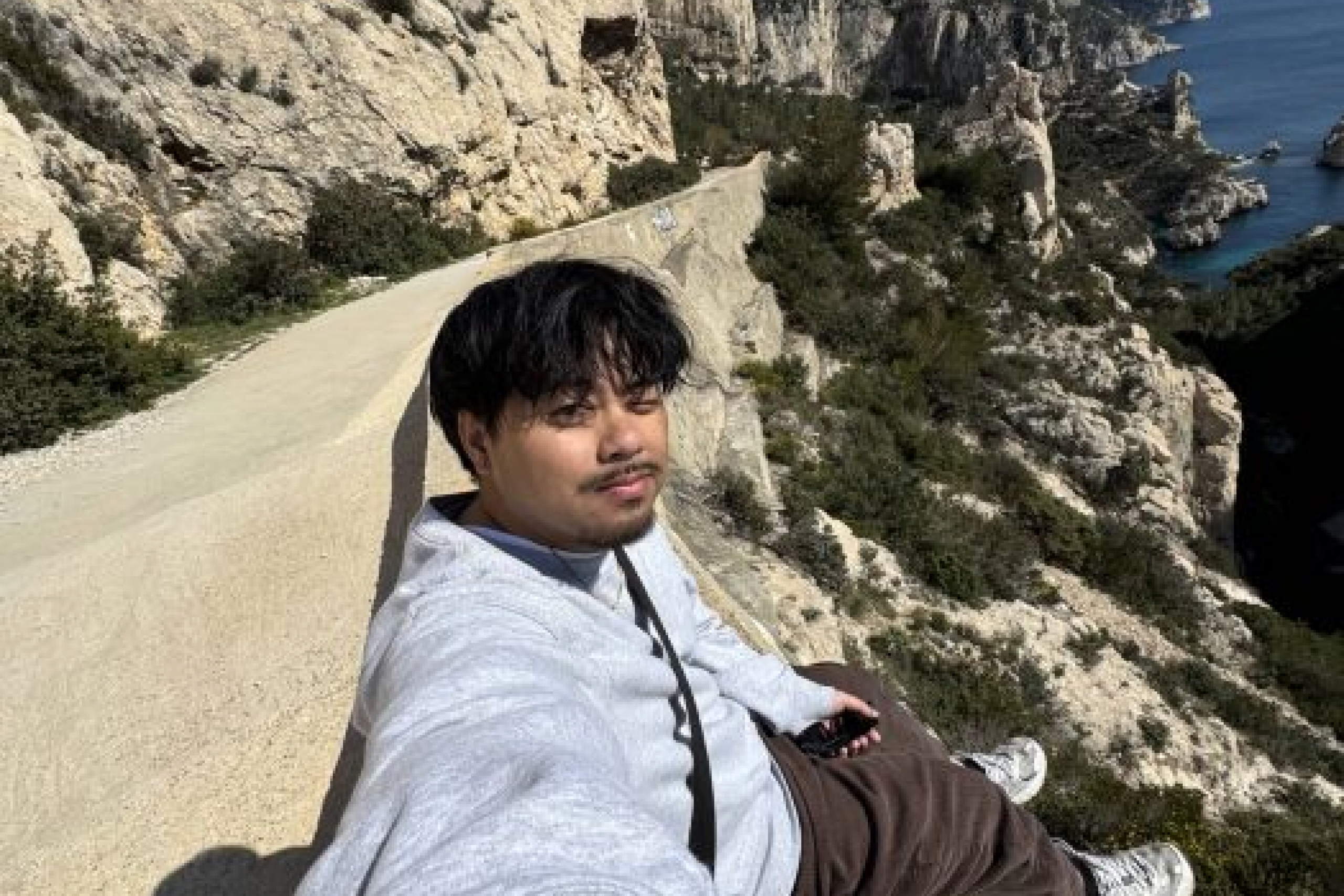 Mickael Gier smiling on a lookout with the ocean in the background