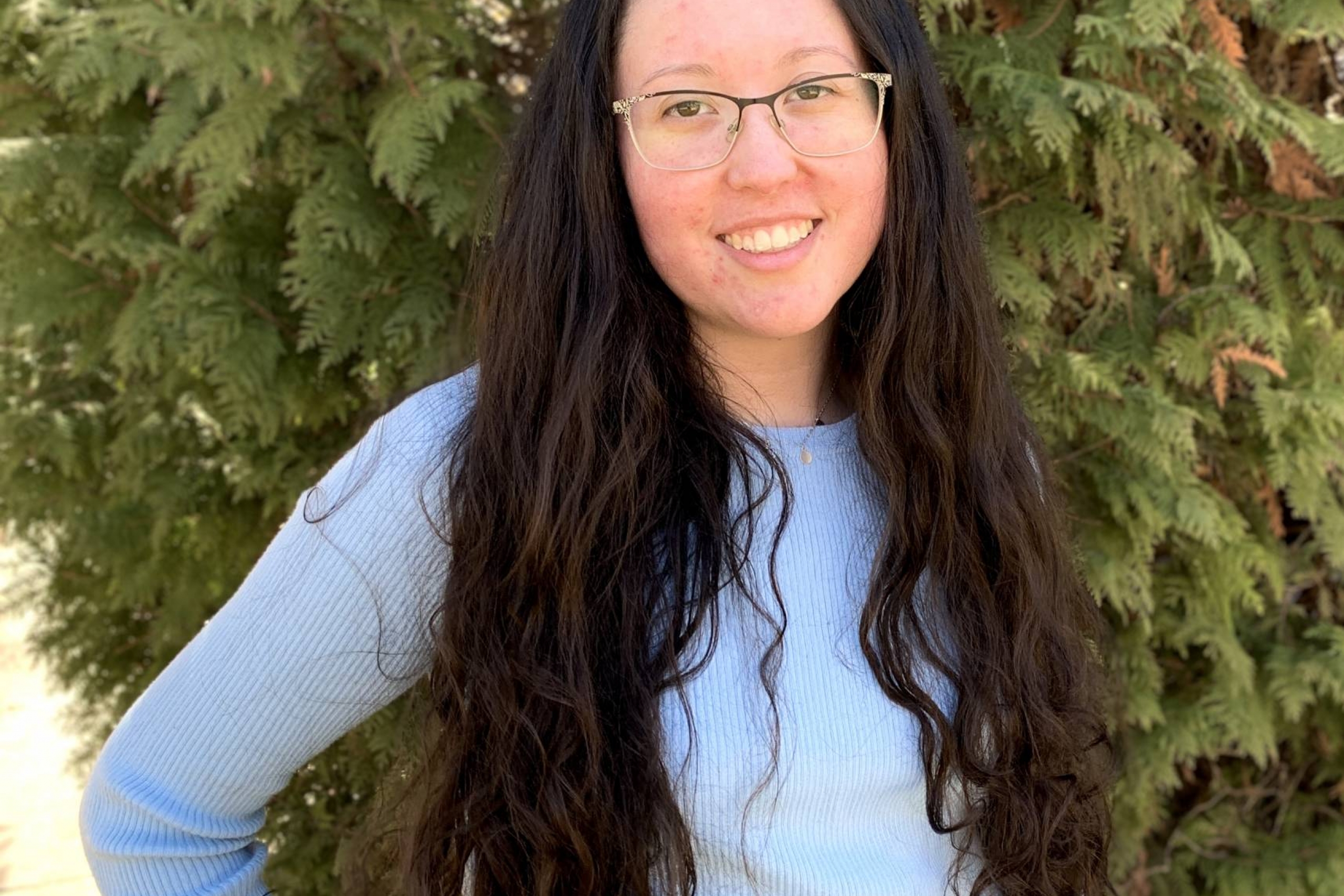 girl with glasses and long hair wearing blue sweater