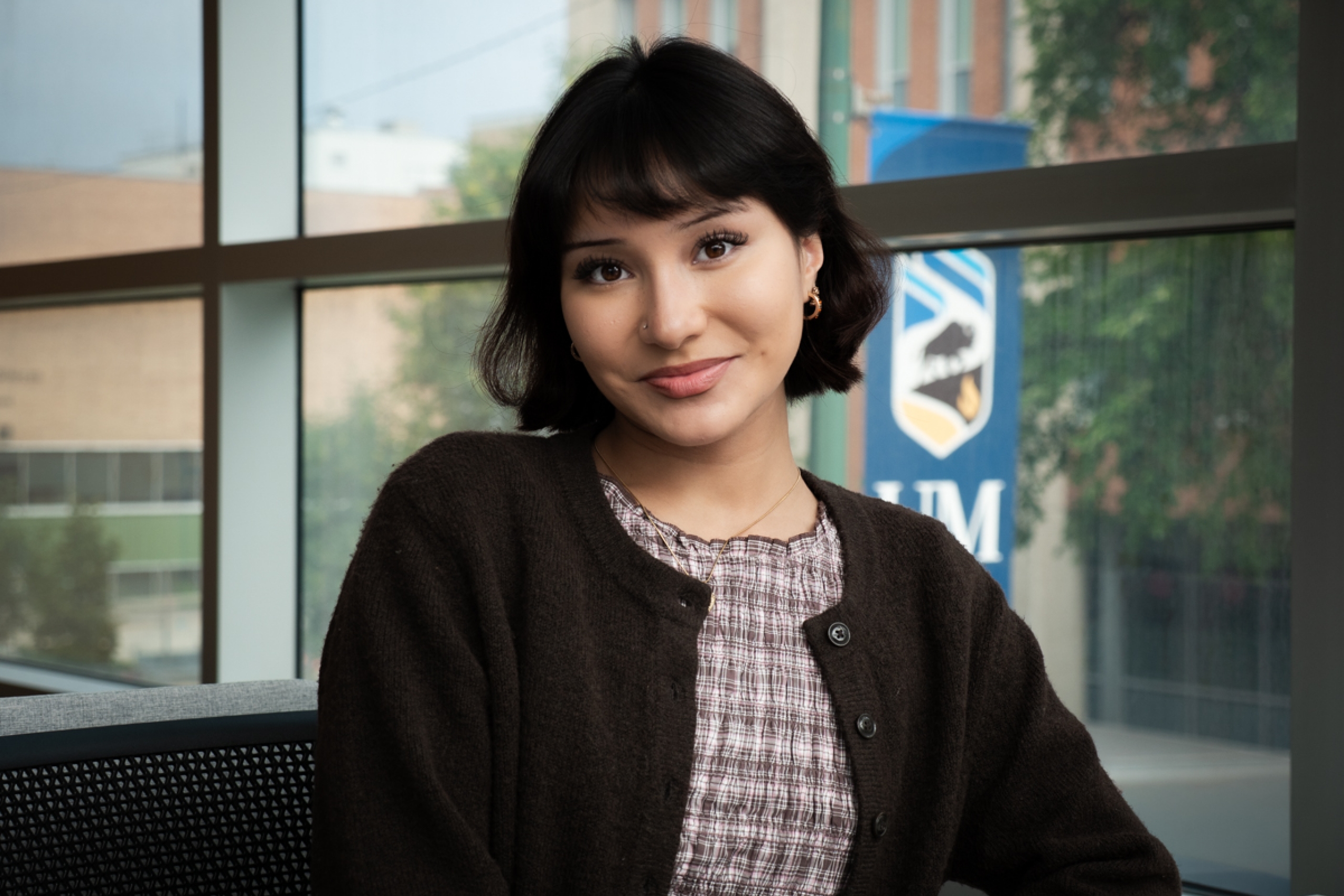 A student smiling, in the background is a UM logo.