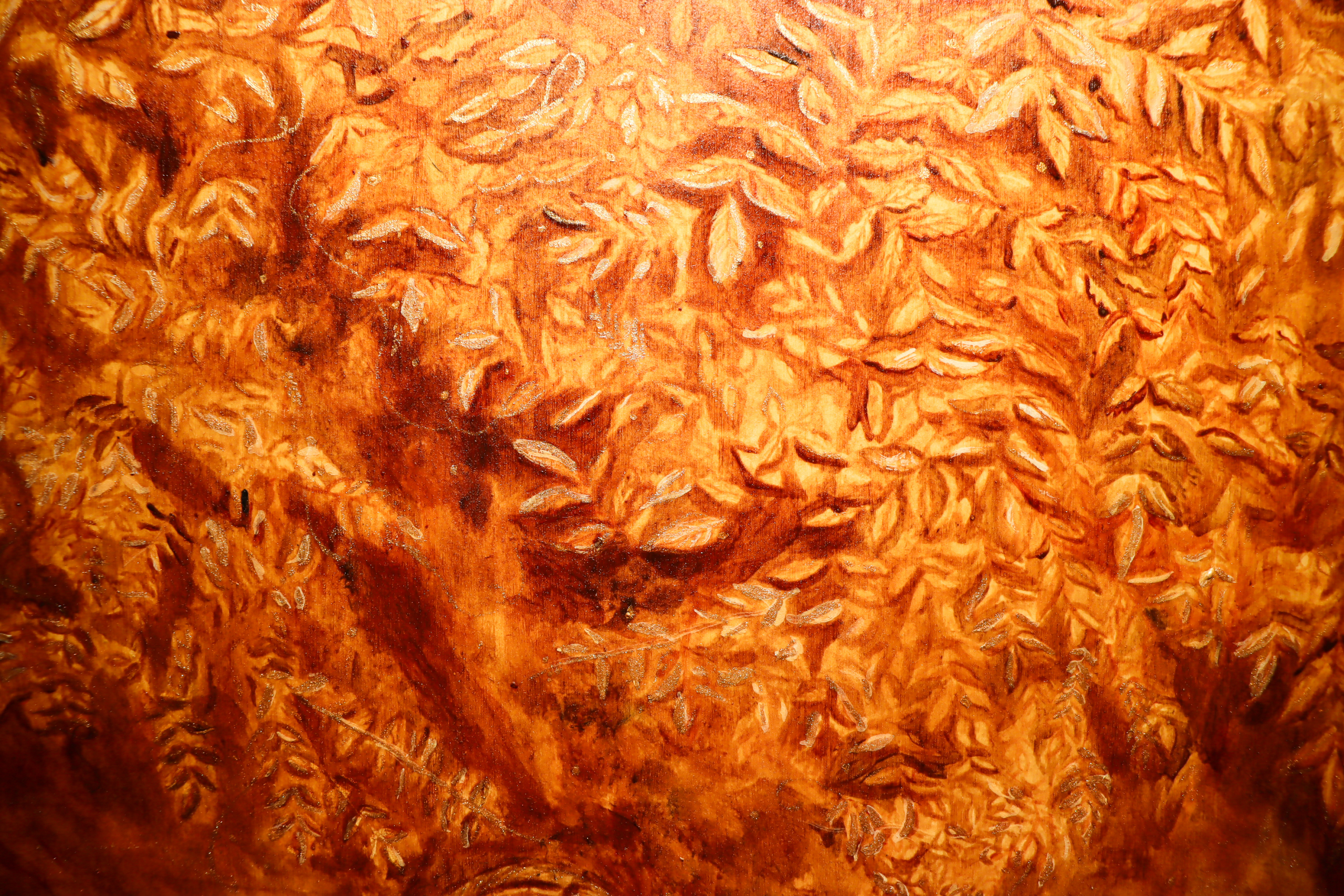 Close-up detail of a warm-toned painting surface filled with layered leaf shapes and textured brushwork.