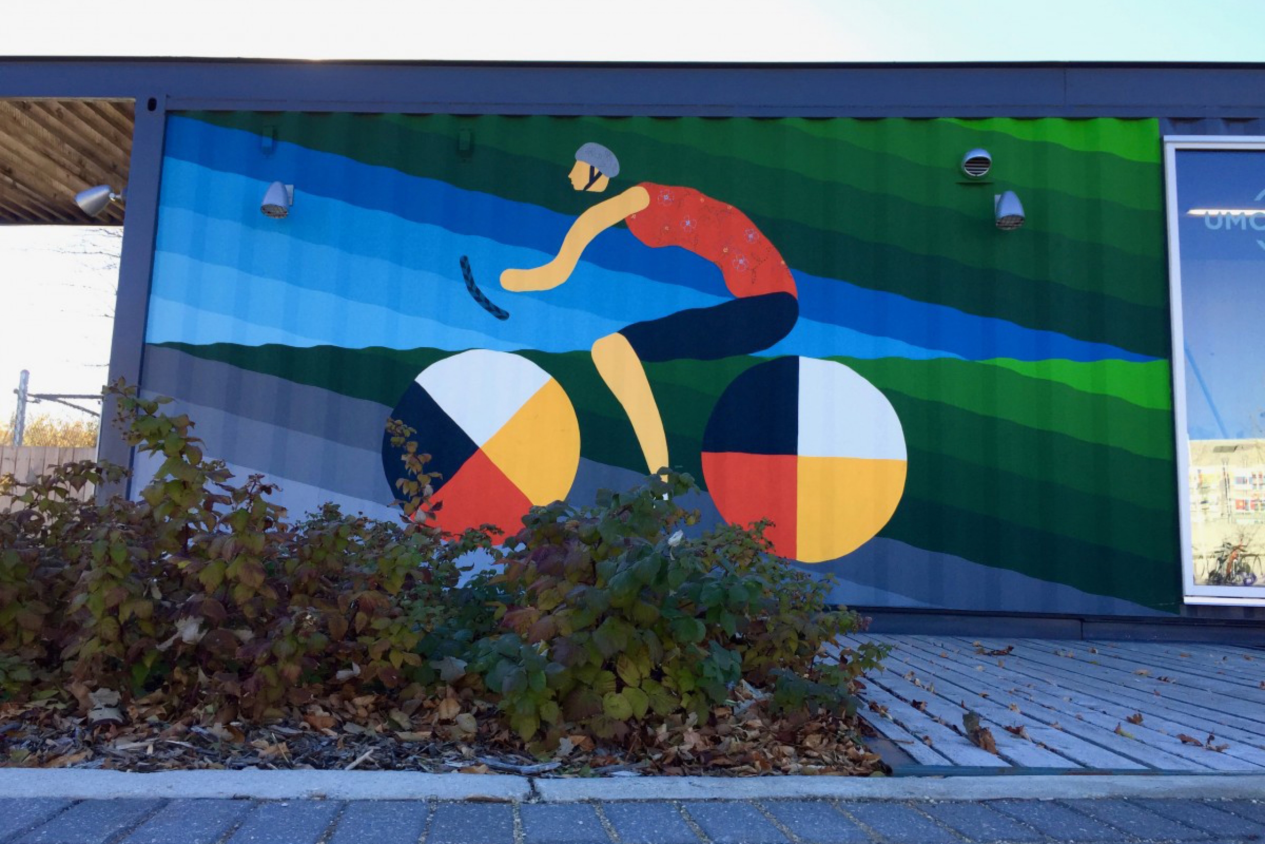 Colourful mural of cyclist at bike kiosk.