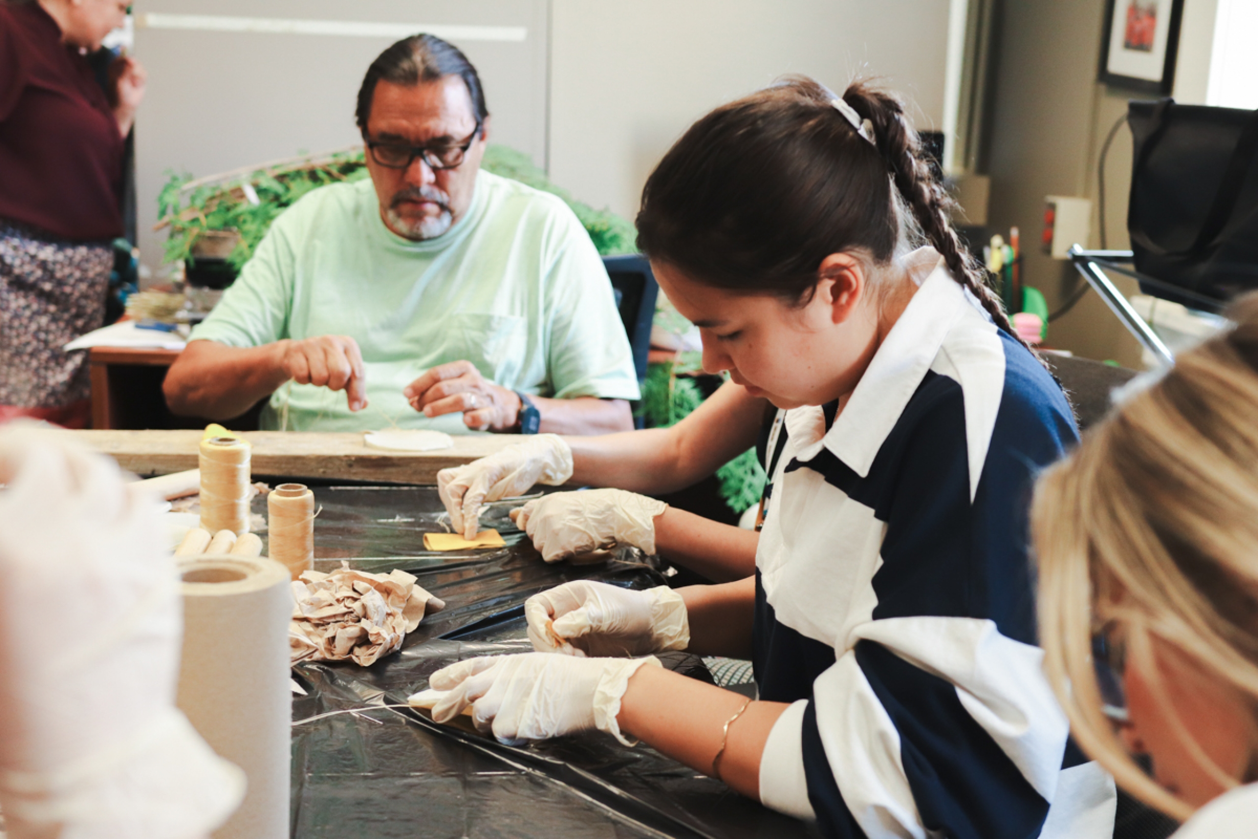 Two people making traditional Indigenous rattles.