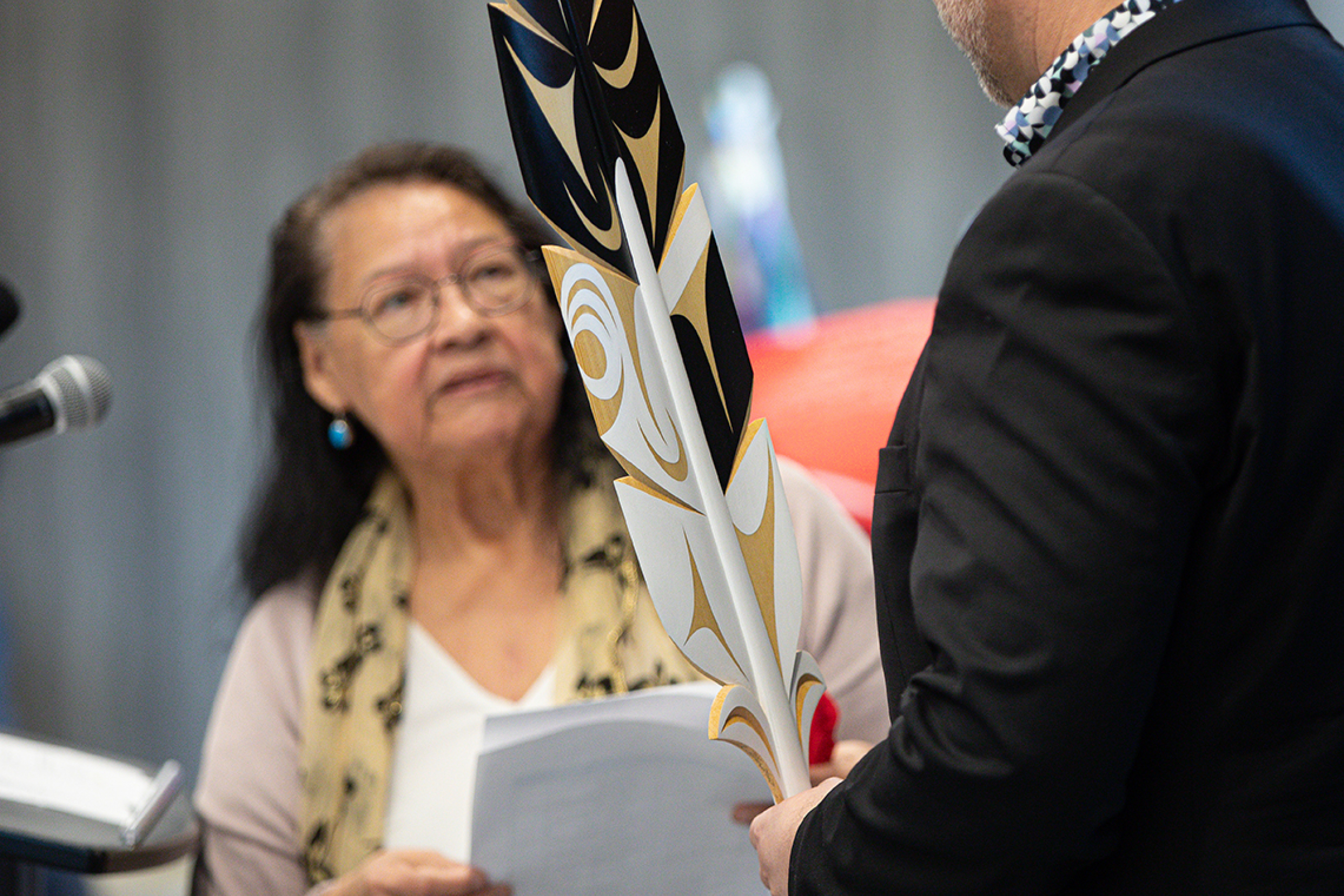 An Elder presenting a feather statue to Sky Bridges