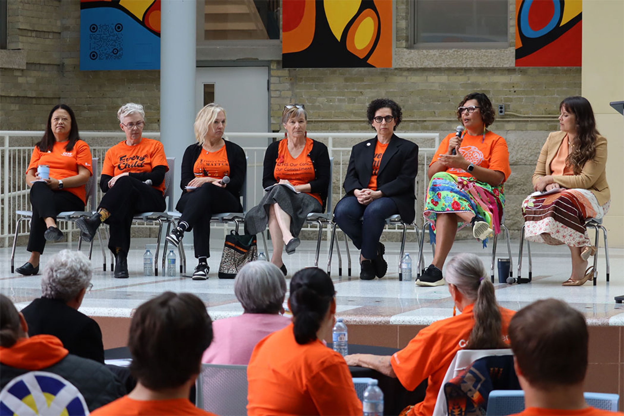 Seven people on stage in orange shirts