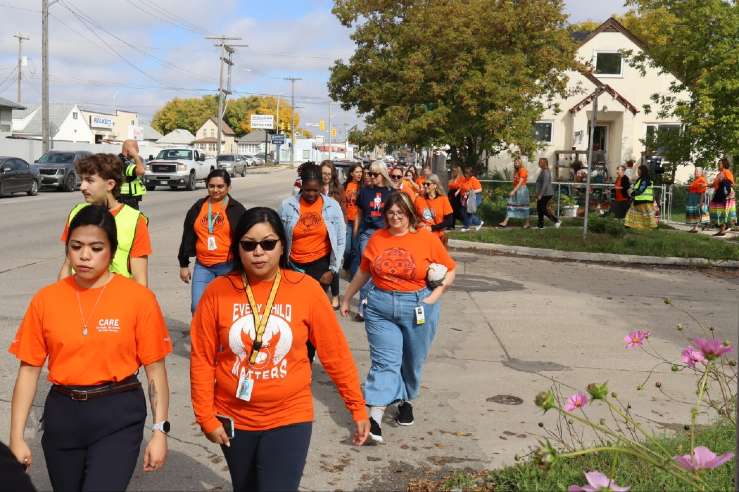Group of people wearing orange shirts crossing the street together.