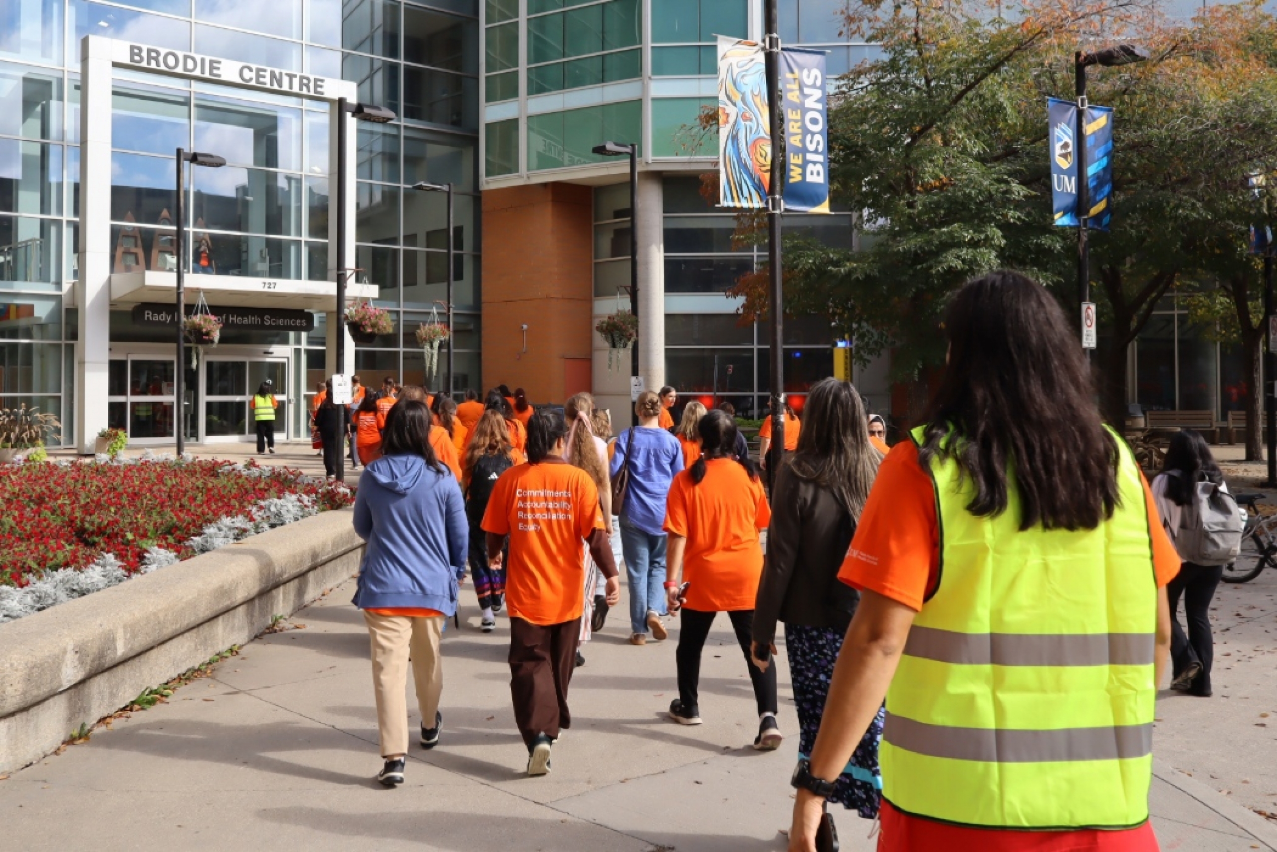 Group of people wearing orange shirts walking toward Brodie Centre.