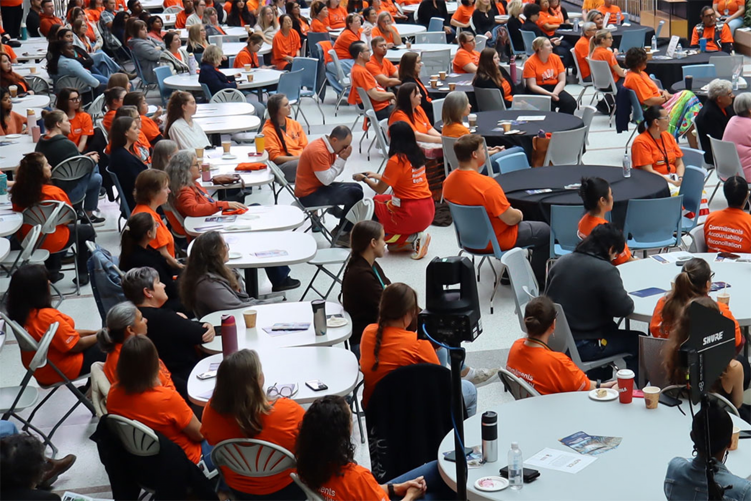 Crowd of people wearing orange shirts with a person smudging.