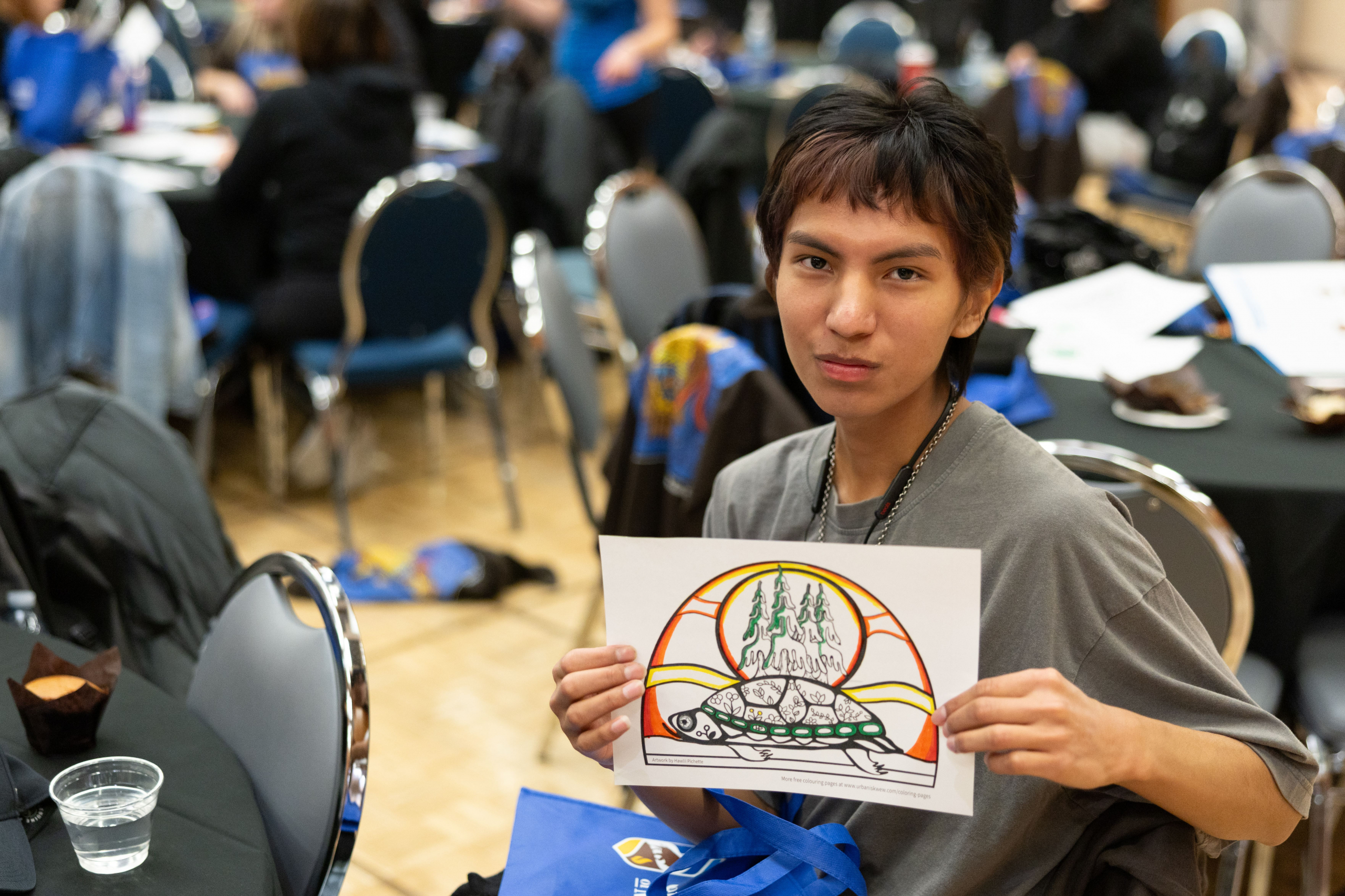 Student poses with Indigenous-inspired artwork.