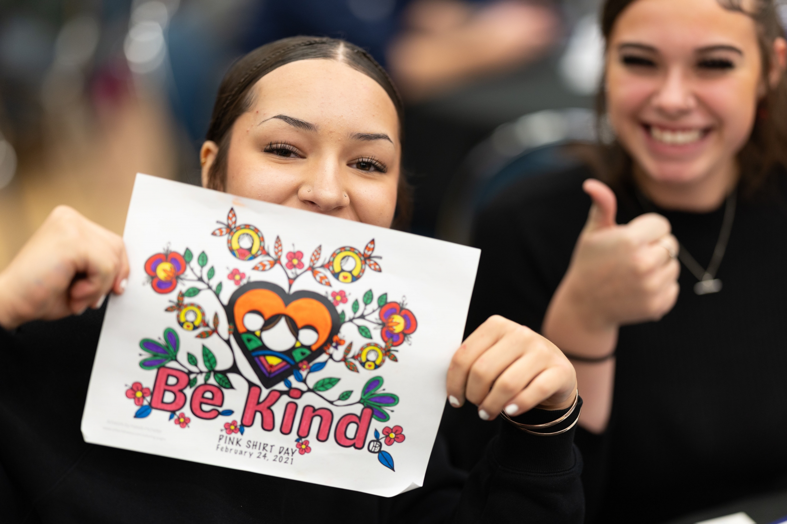 Student poses with Indigenous-inspired artwork.
