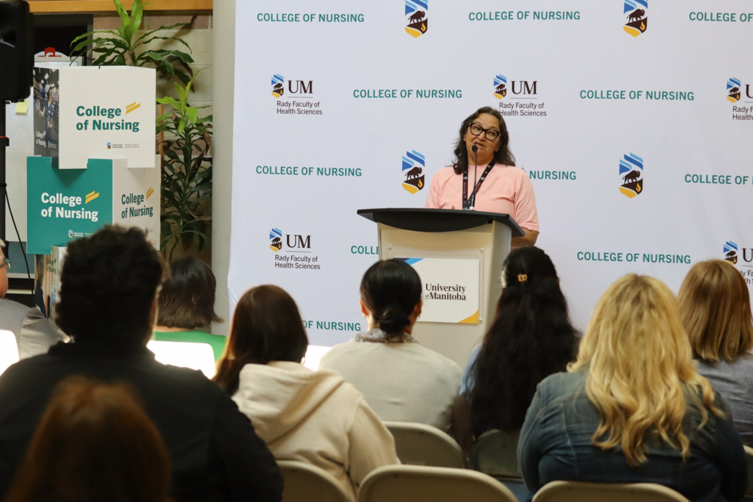 A person talks behind a podium. In front a crowd is gathered.