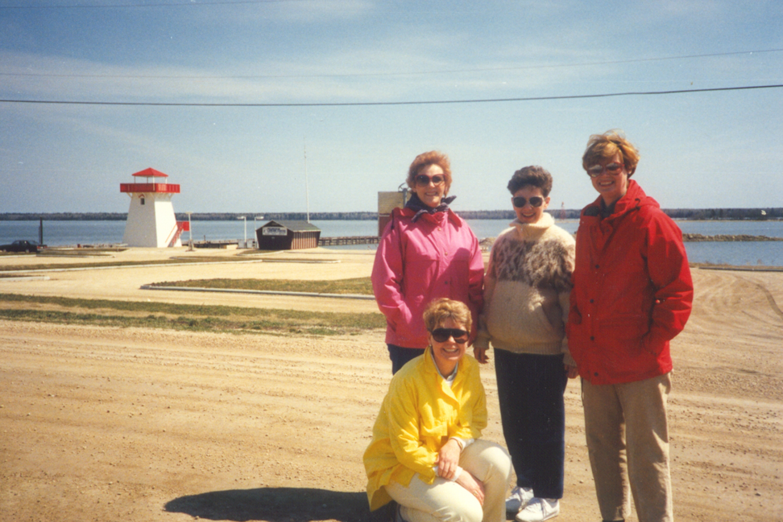 Group photo of four people. In the background you can see the Hecla shoreline. 