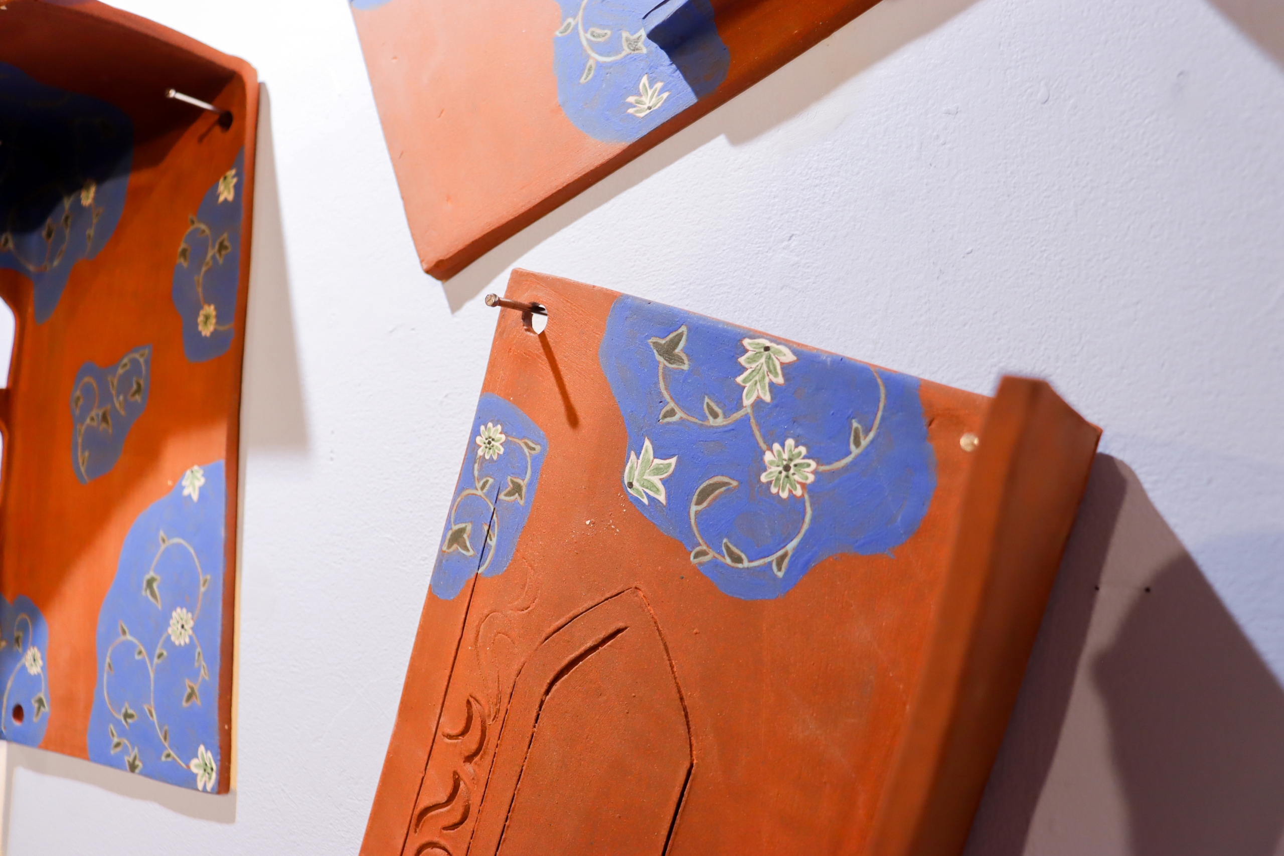 Painted ceramic wall pieces with blue floral patterns on orange surface