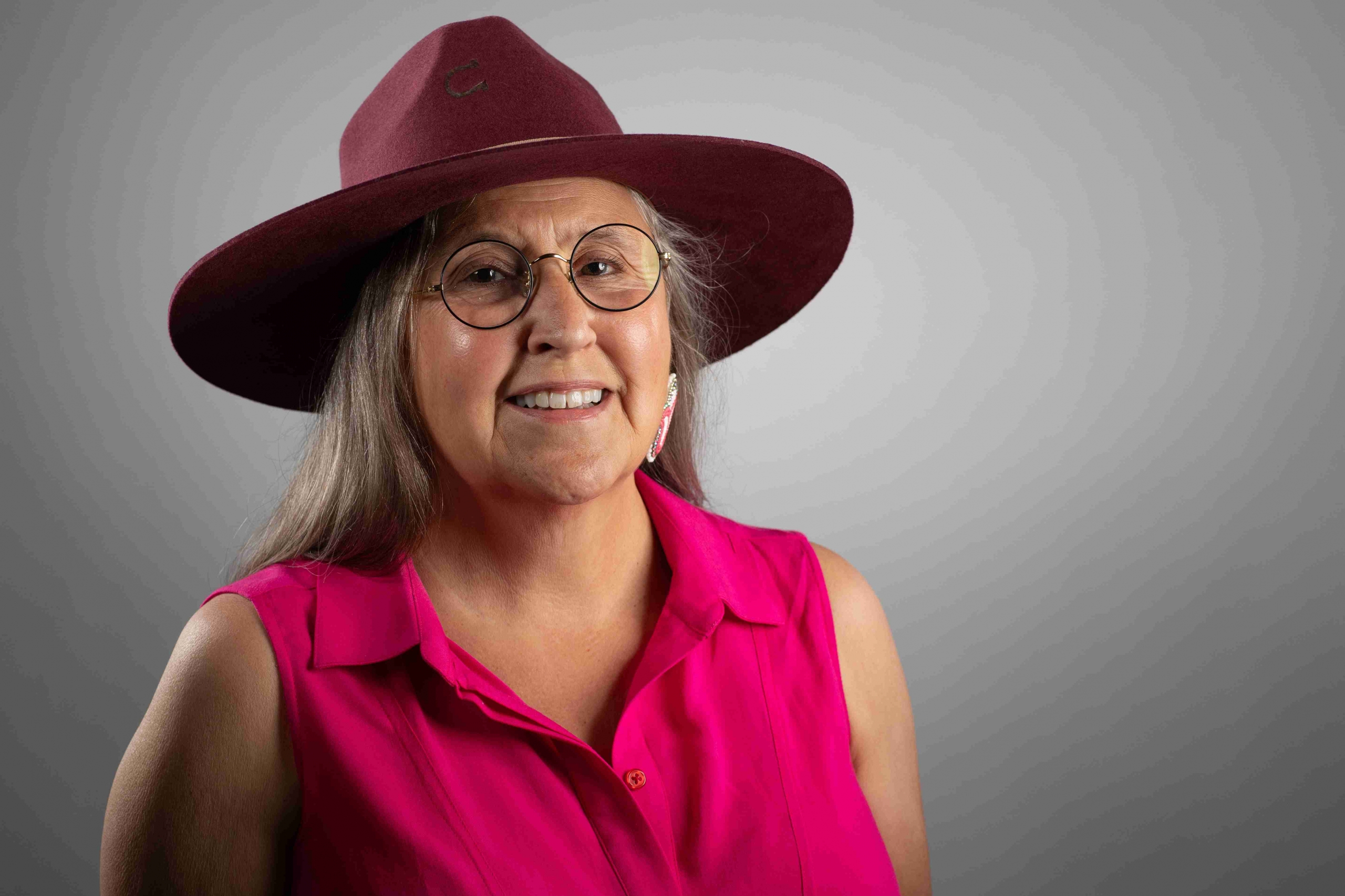 portrait of smiling woman wearing a pink hat and top.