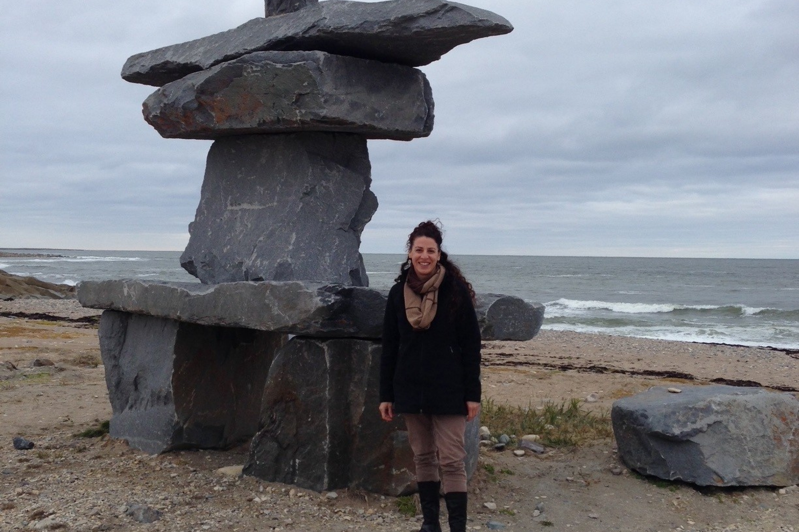 Pam Becker next to an inuksuk on a beach in Churchill, Manitoba.