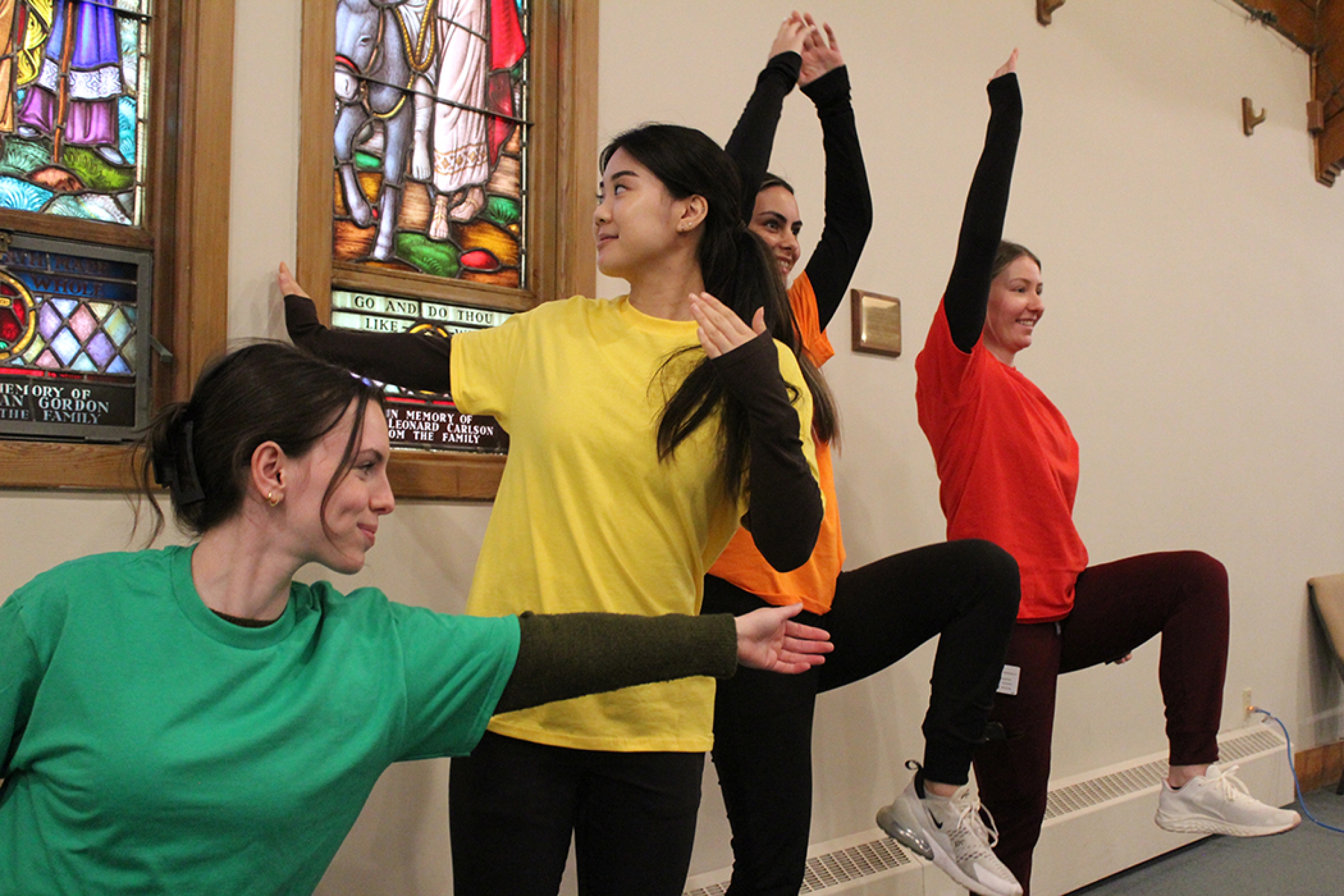 Physical therapy students lead a community workshop in a church, wearing colour-coded shirts.