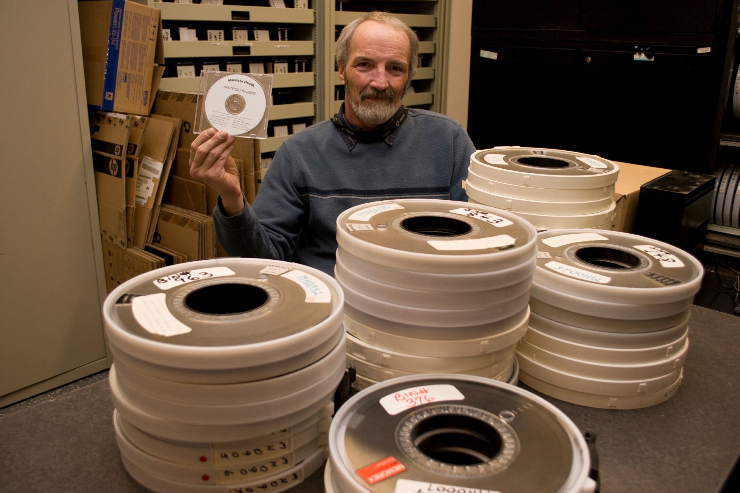 A person hold a cd and in front are many film reels.
